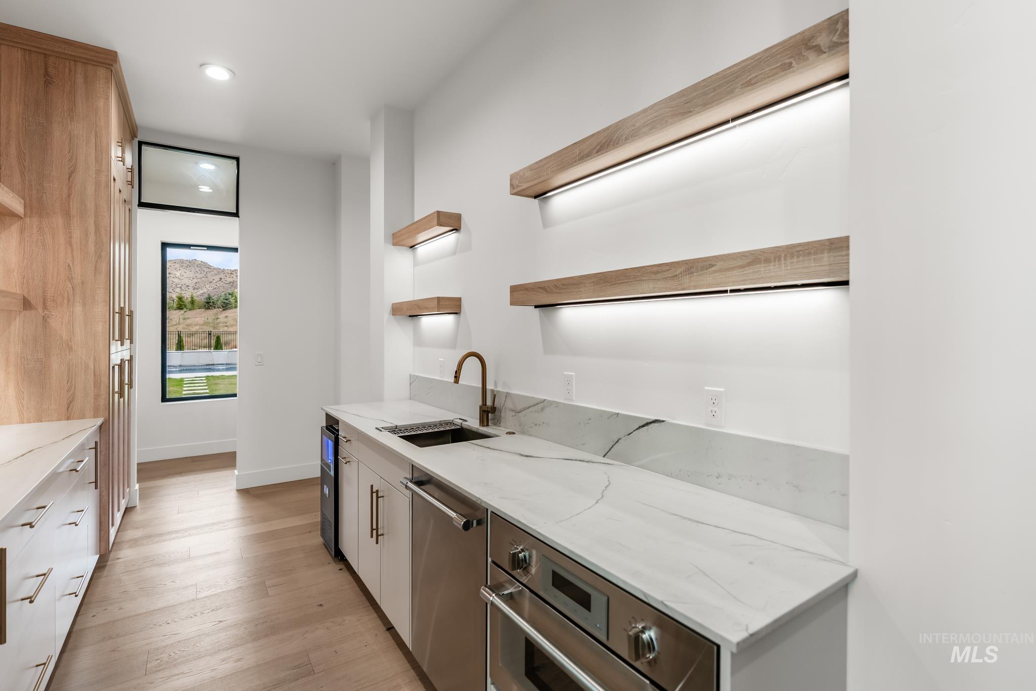 Kitchen with open shelves, light stone counters, appliances with stainless steel finishes, light wood-style floors, and recessed lighting