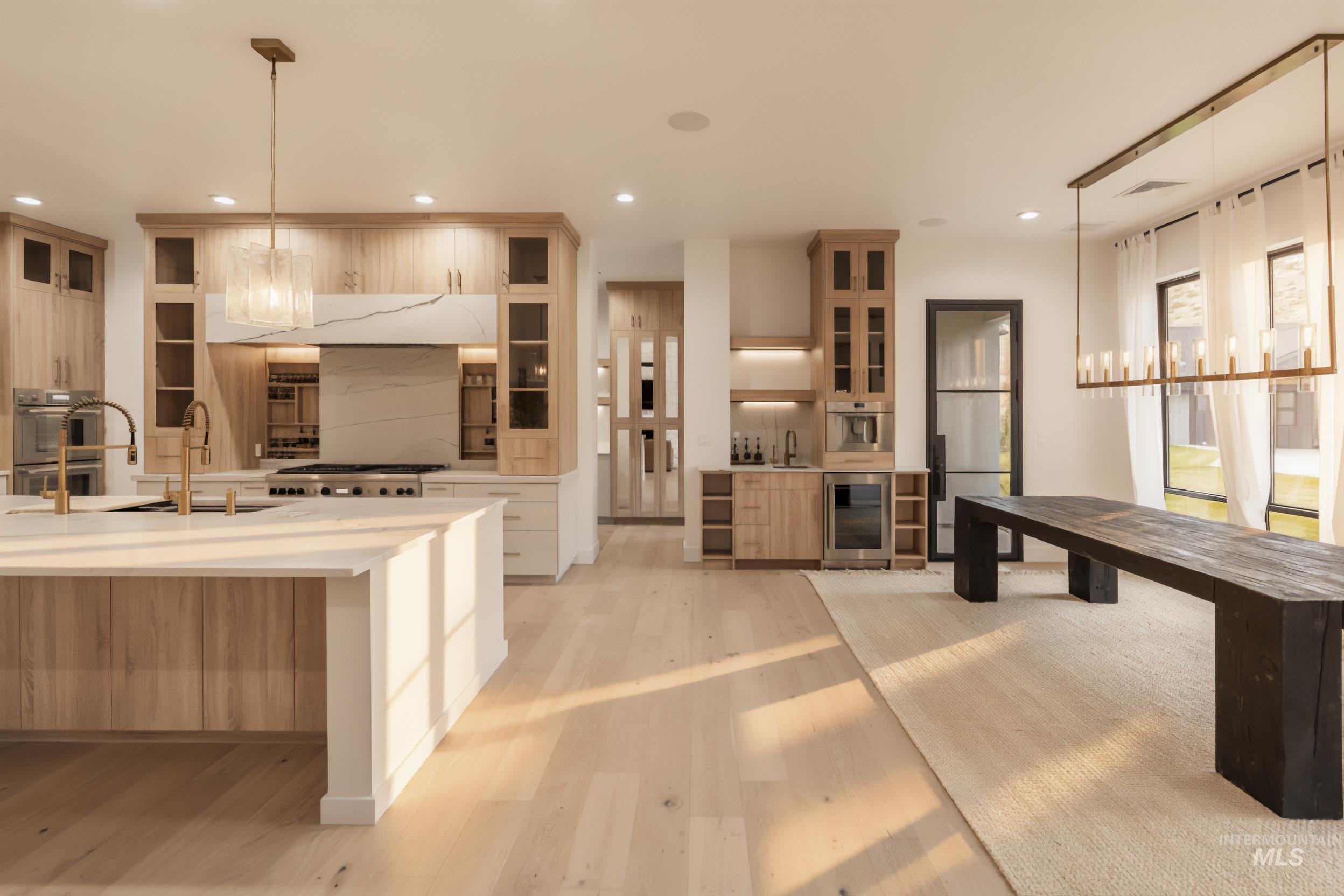 Kitchen with pendant lighting, light stone counters, wine cooler, light wood-type flooring, and recessed lighting