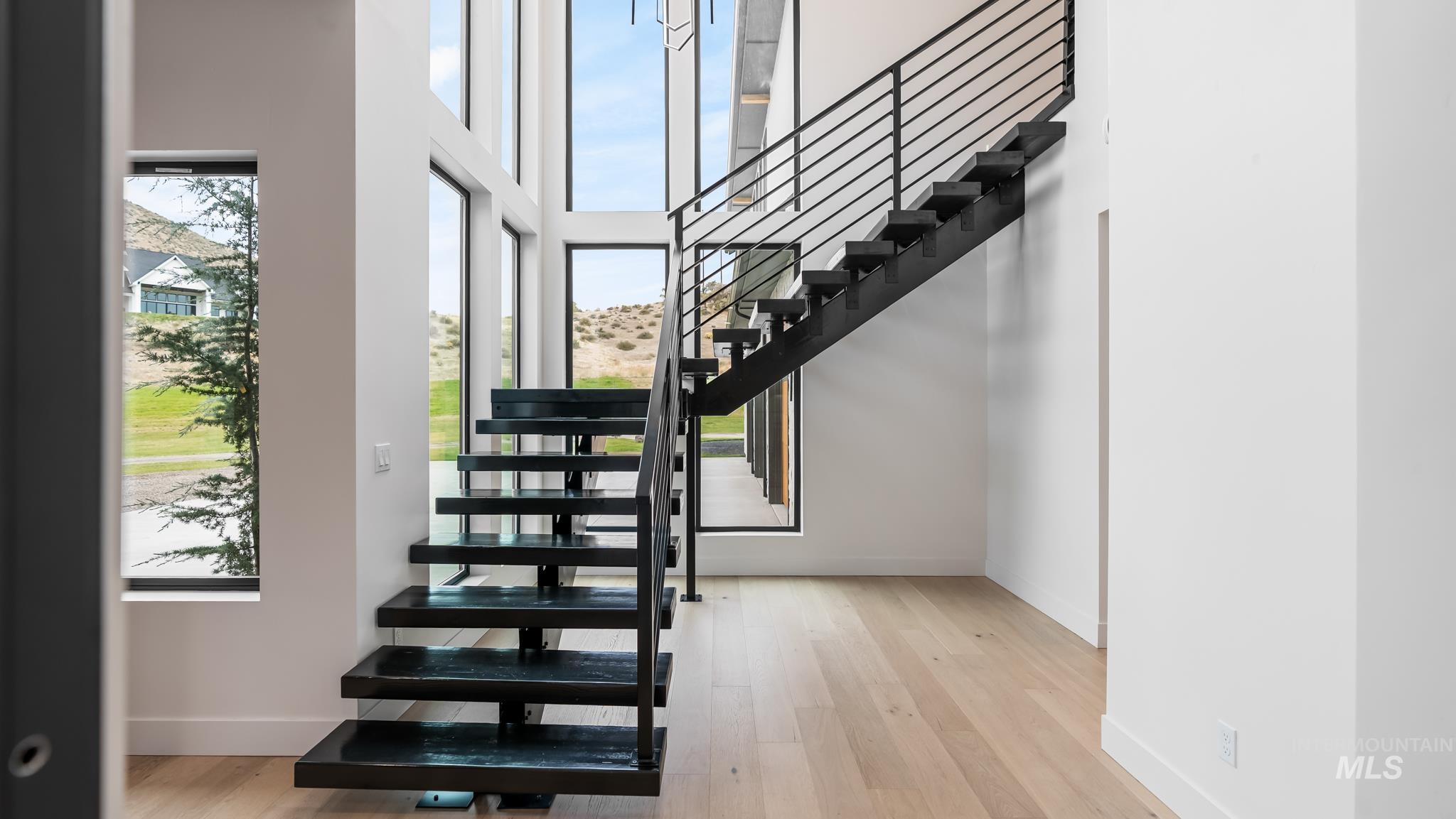 Stairs with wood finished floors and a high ceiling