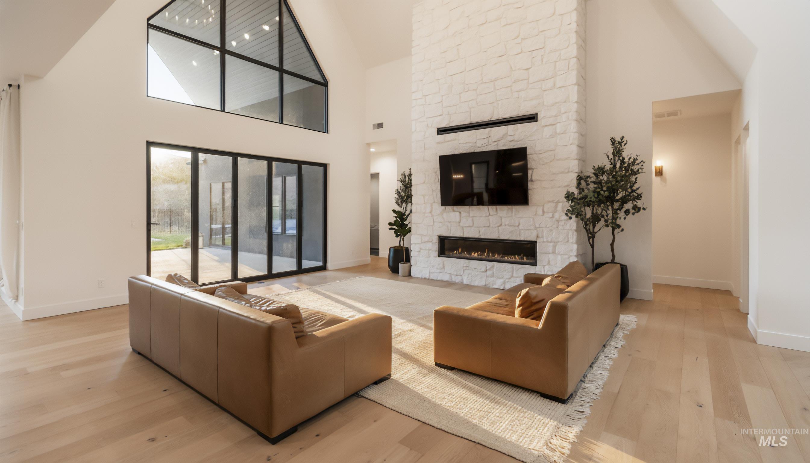 Living room with high vaulted ceiling, a fireplace, and light wood-style flooring
