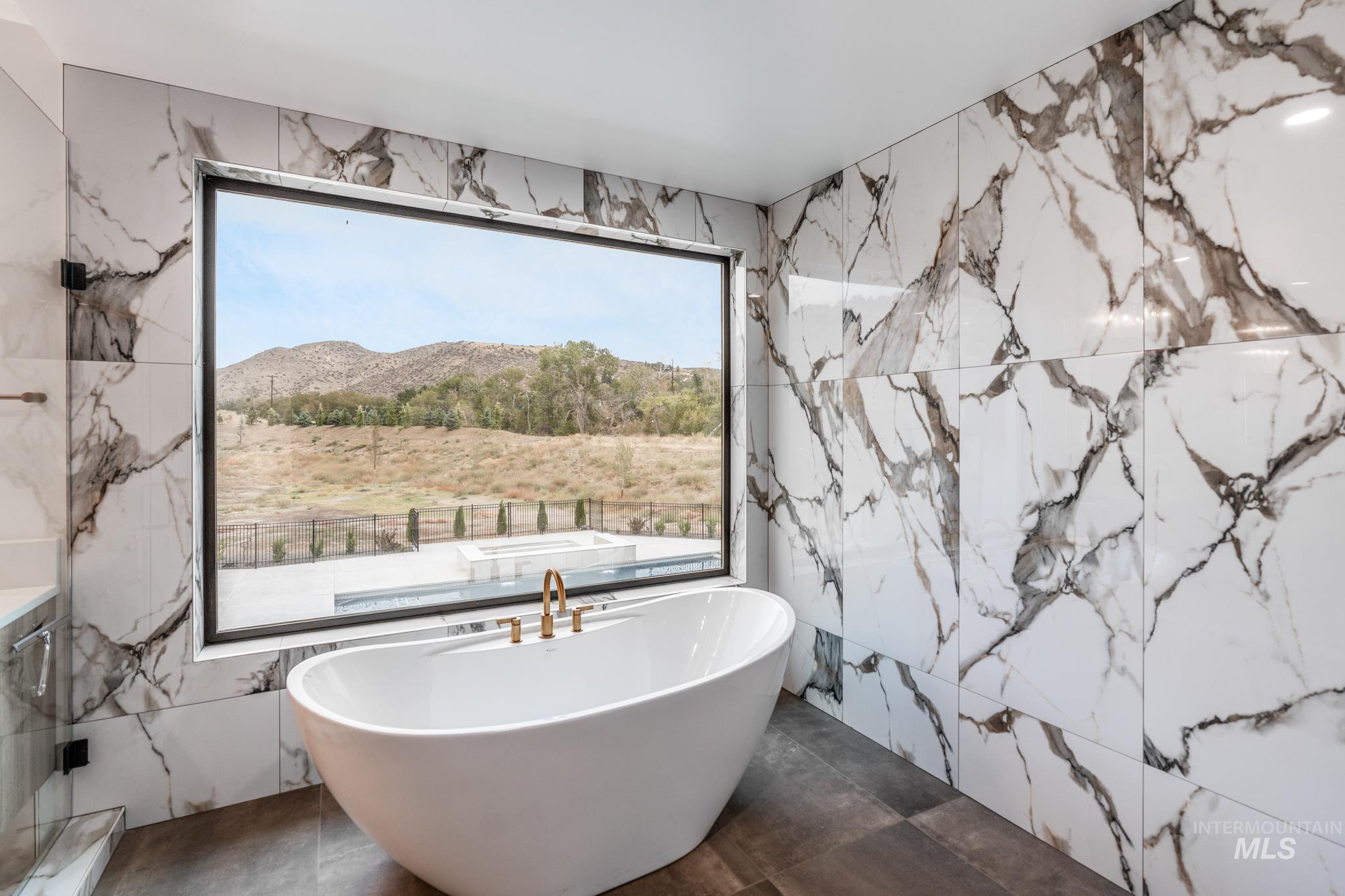 Full bath featuring a freestanding bath, stone wall, tile walls, and a mountain view