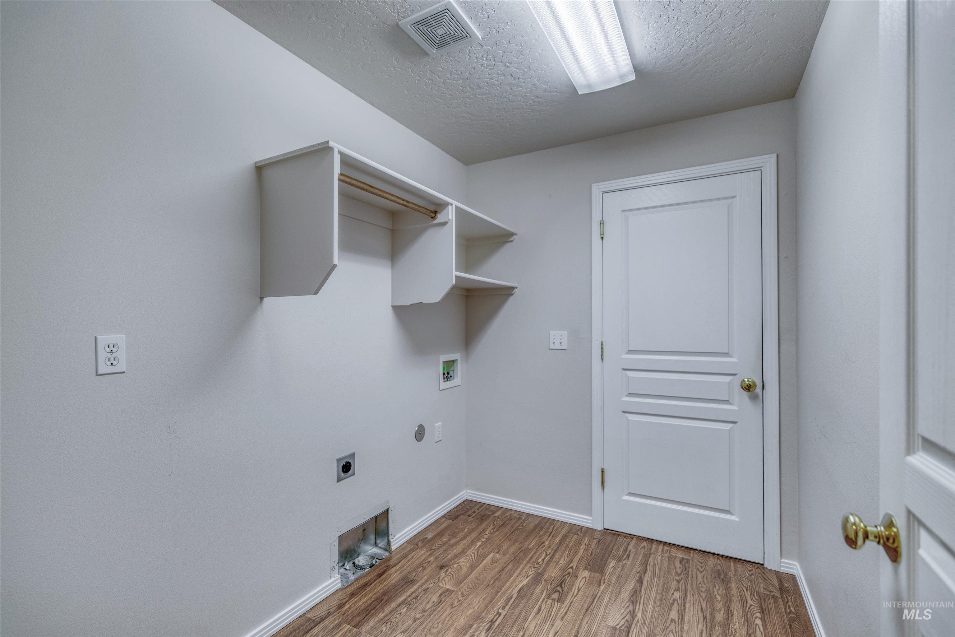 Laundry area with light wood-type flooring, a textured ceiling, electric dryer hookup, washer hookup, and hookup for a gas dryer