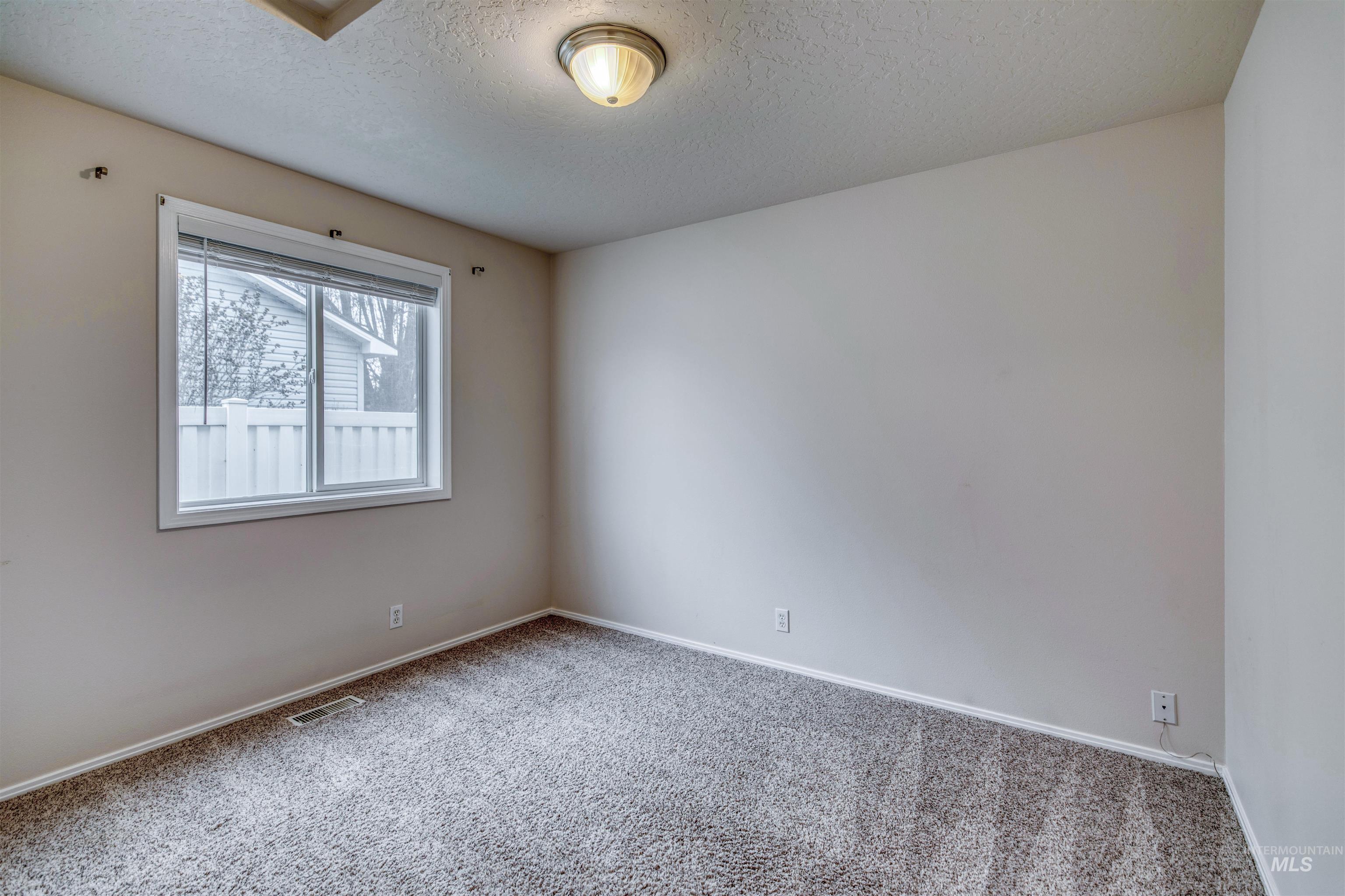 Carpeted spare room with a textured ceiling