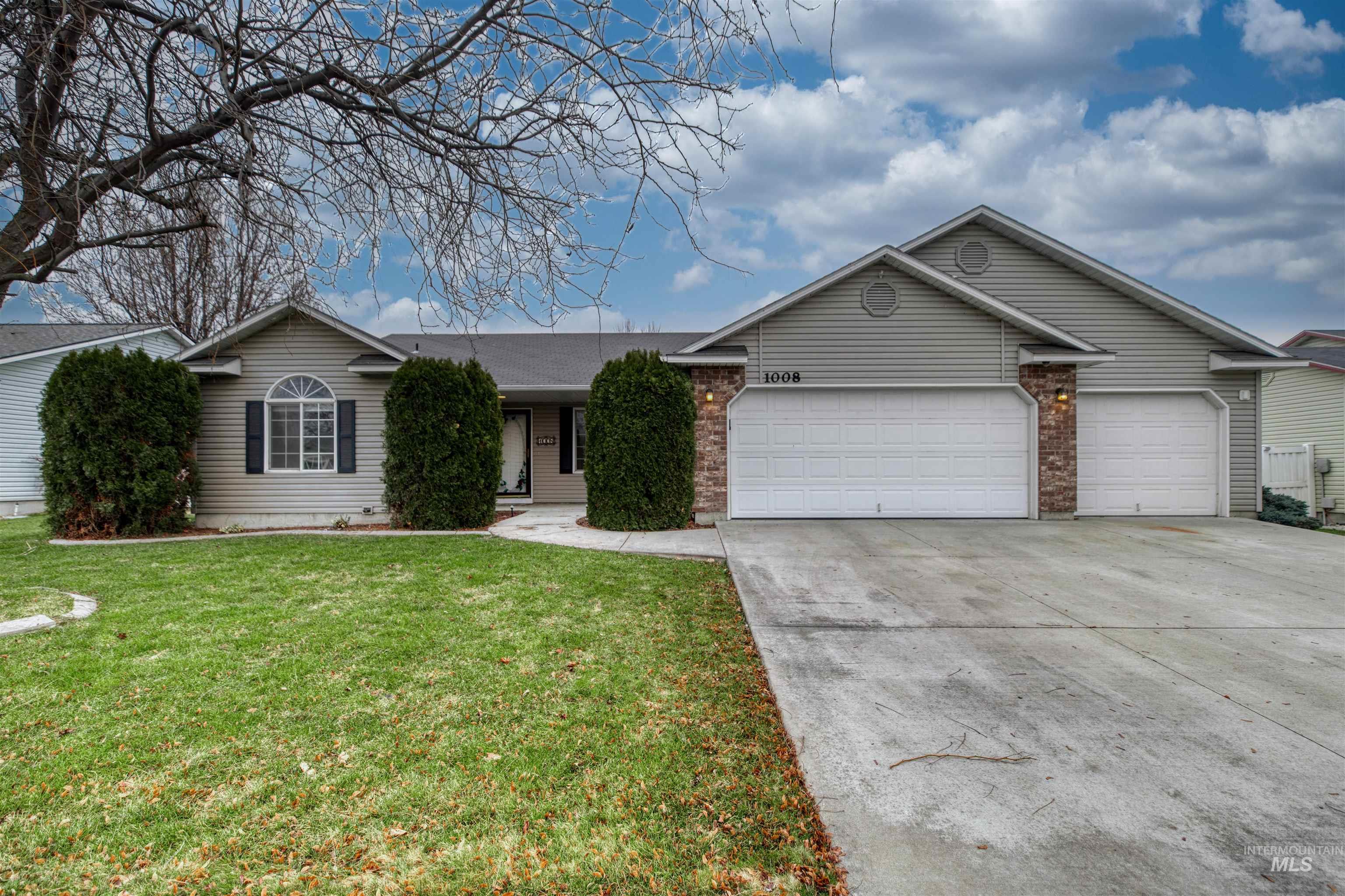 Single story home featuring driveway, an attached garage, a front lawn, and brick siding