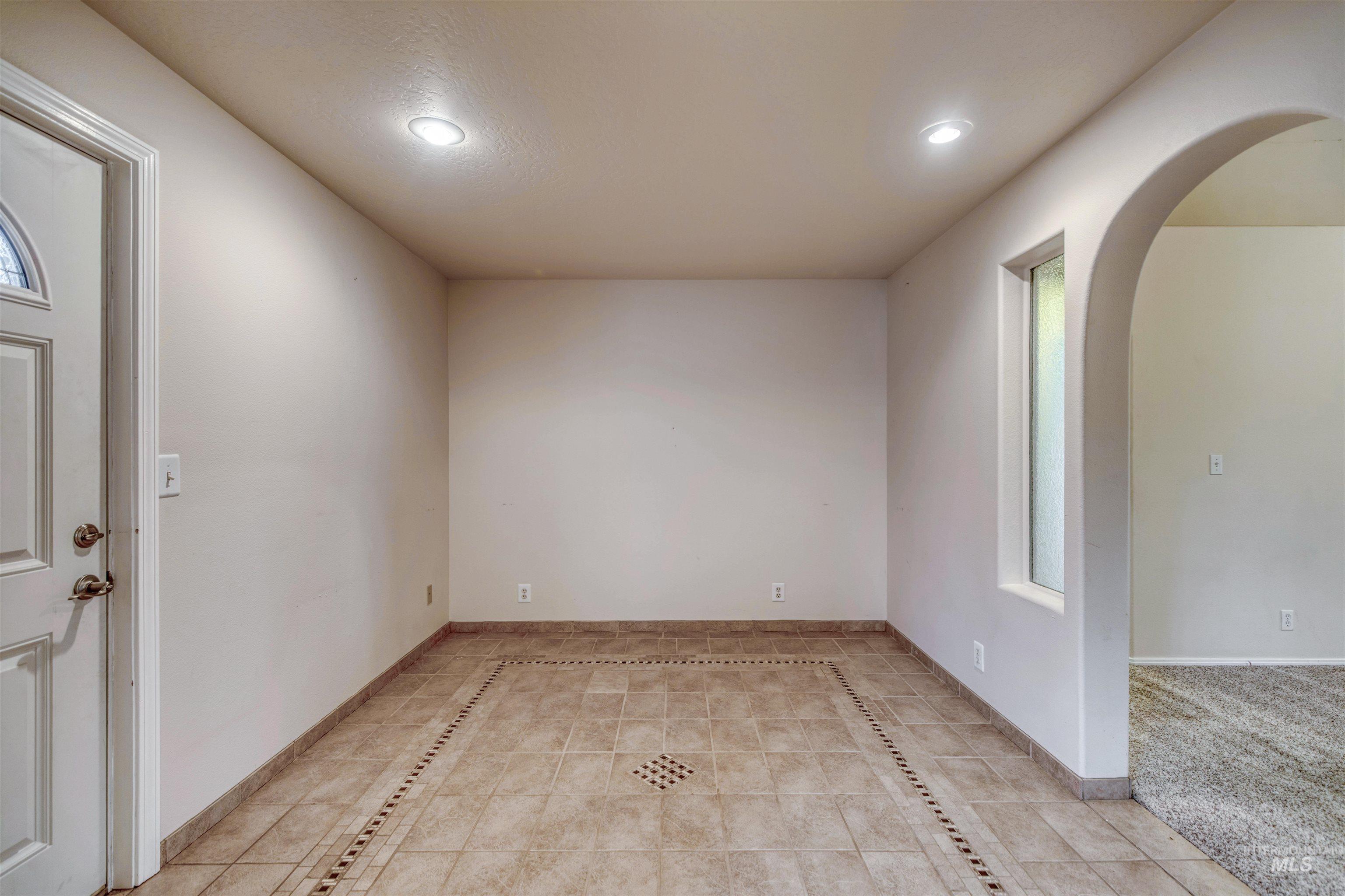 Empty room featuring arched walkways, light tile patterned floors, healthy amount of natural light, recessed lighting, and inlaid floor details
