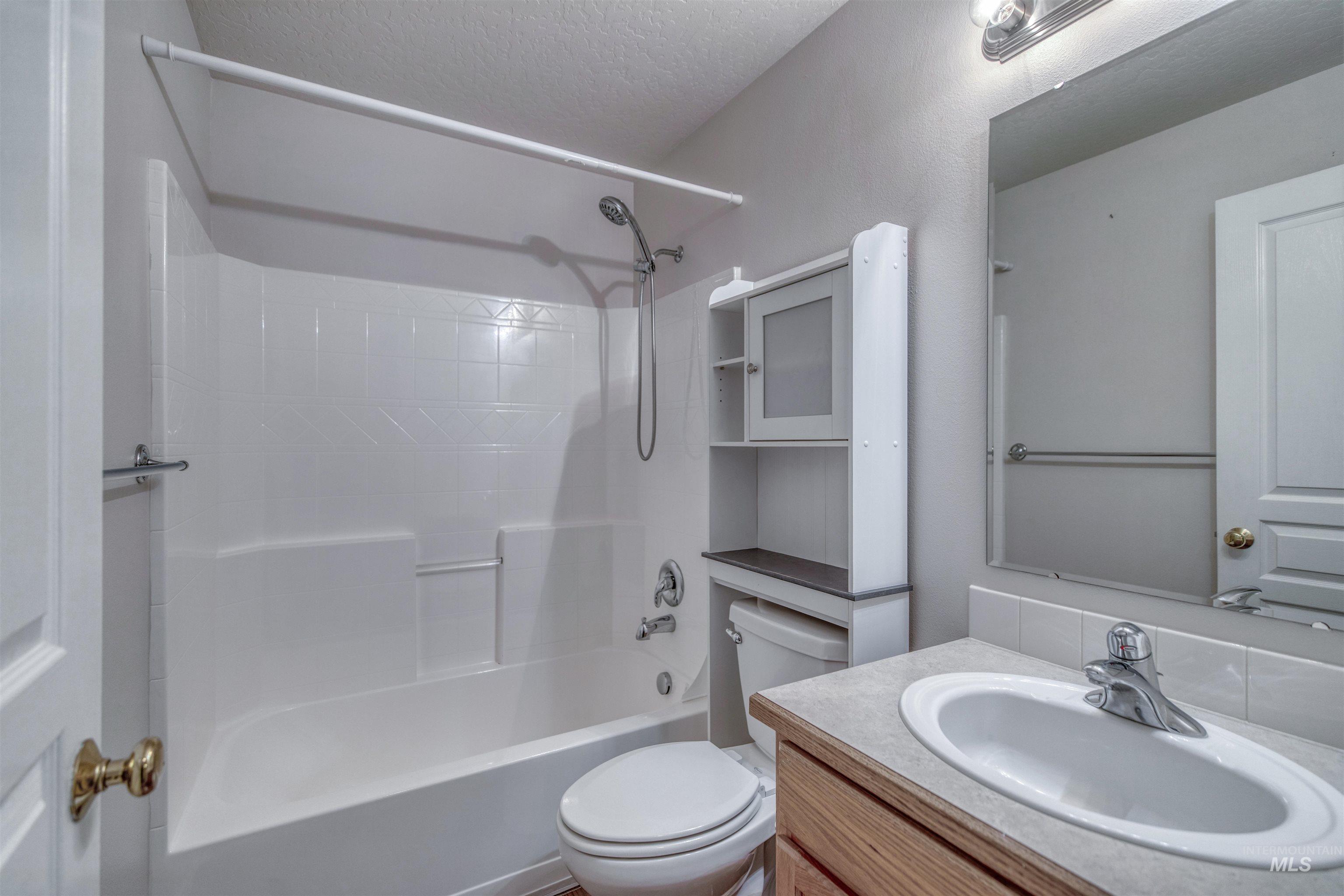 Bathroom with vanity, shower / washtub combination, and a textured ceiling