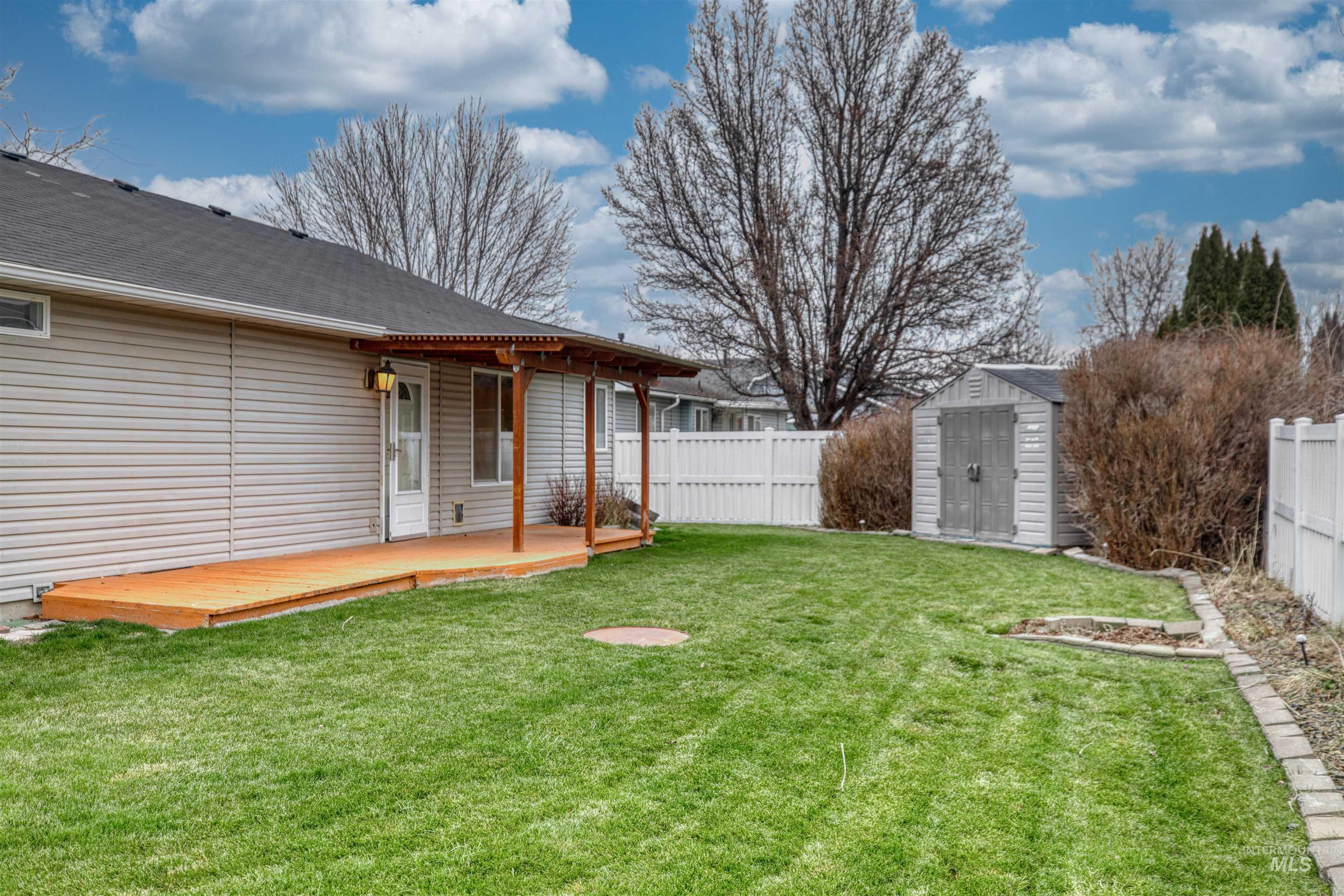 Fenced backyard featuring a storage shed and a deck