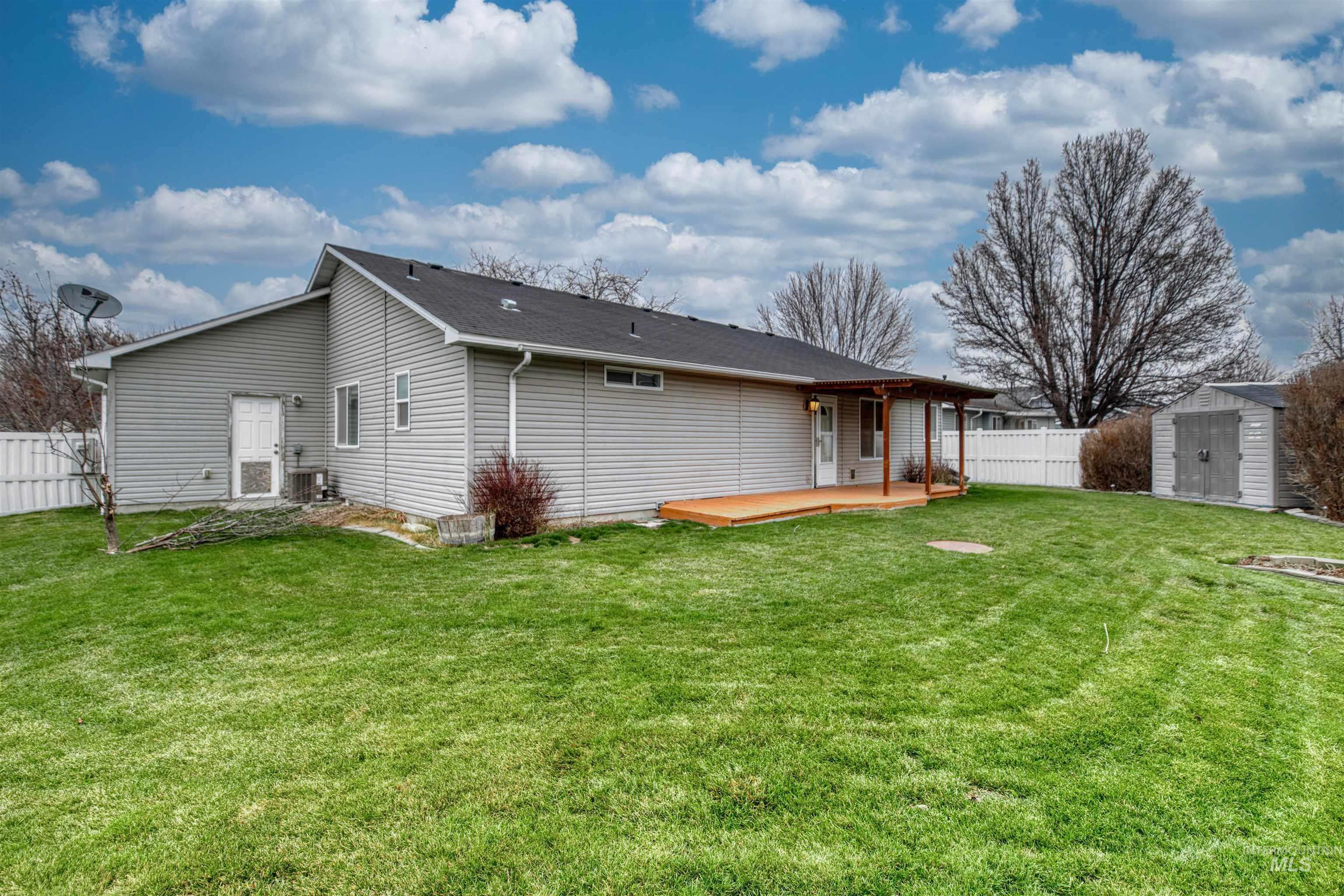 Rear view of house with a fenced backyard, a storage unit, and a deck