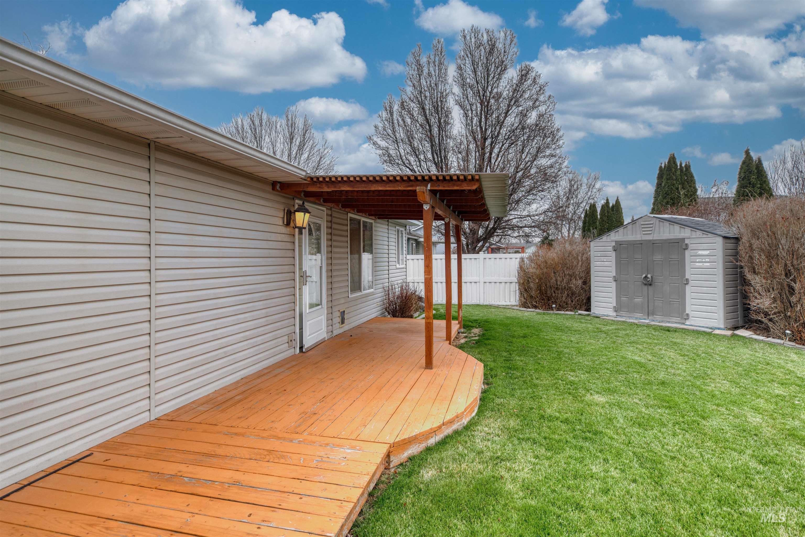 Fenced yard with a wooden deck and a storage unit