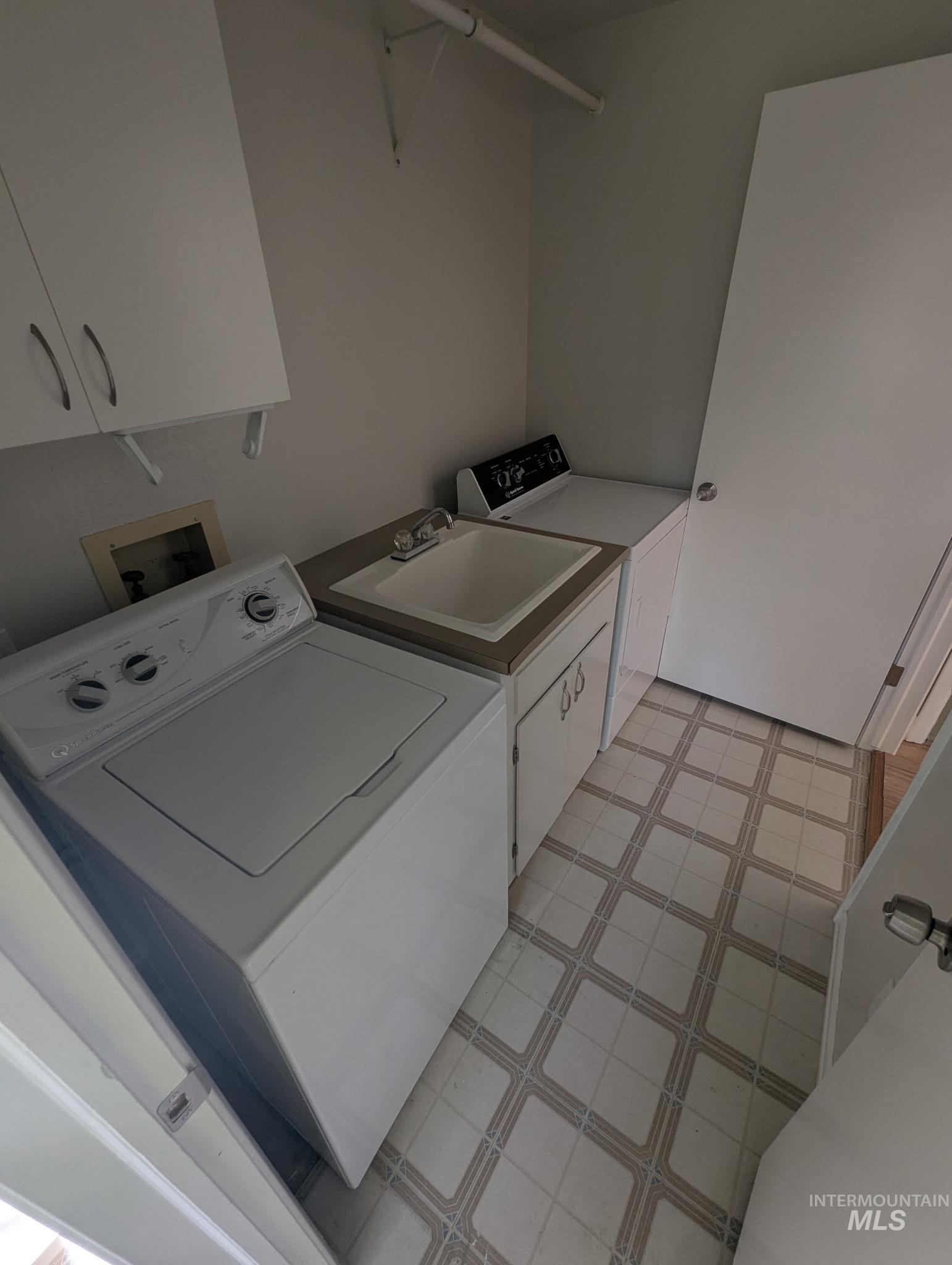 Laundry room with cabinet space, light floors, and washer and dryer