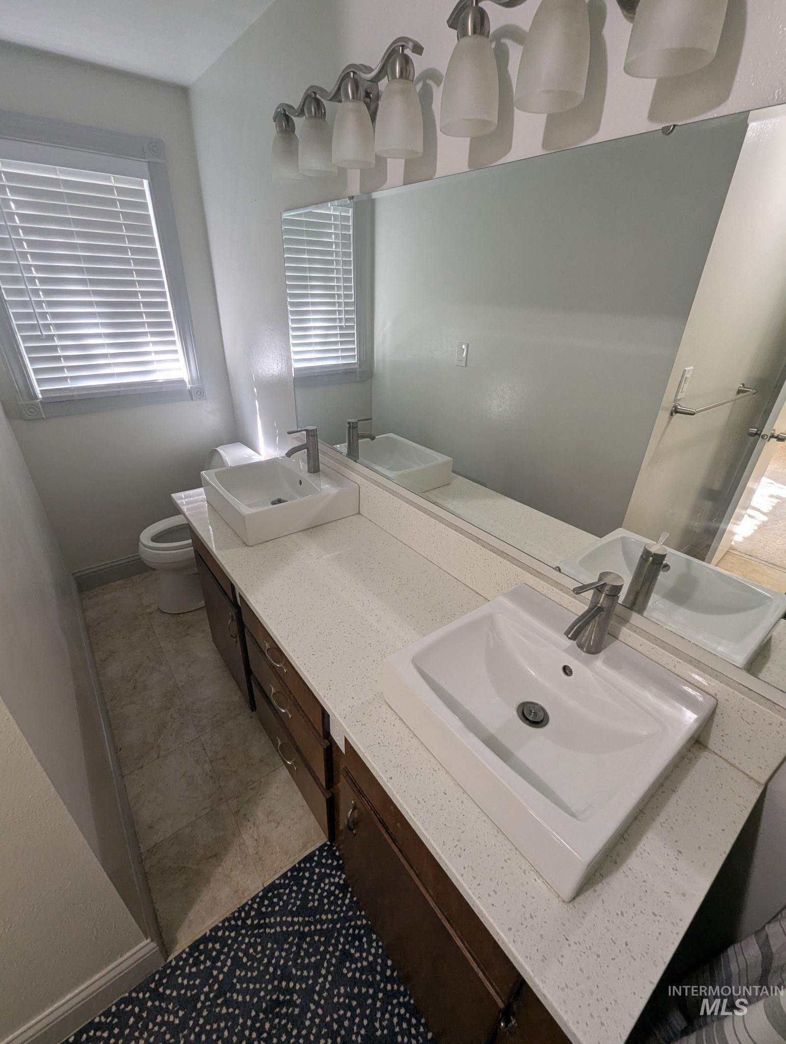 Full bath with double vanity and baseboards