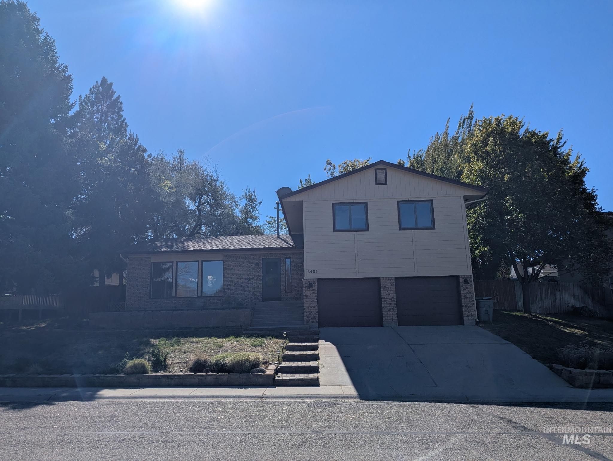 Tri-level home with concrete driveway, brick siding, and an attached garage