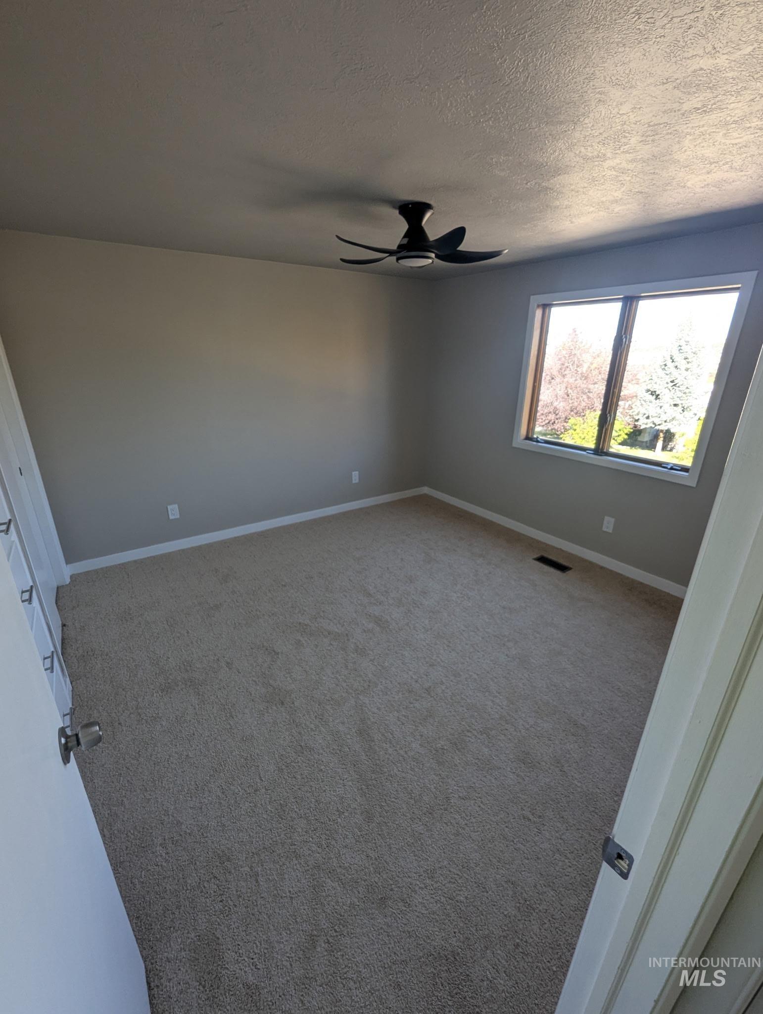 Unfurnished bedroom with carpet, ceiling fan, and a textured ceiling