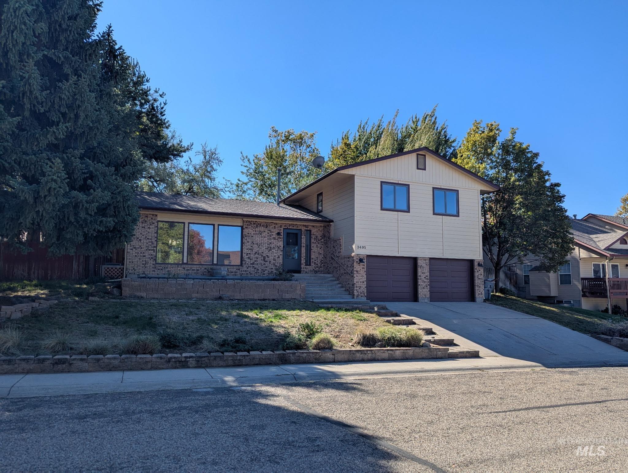 Split level home featuring driveway, brick siding, and an attached garage
