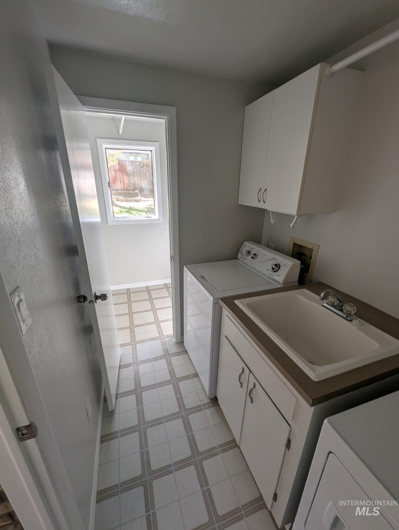 Washroom with cabinet space, light floors, and washer and clothes dryer