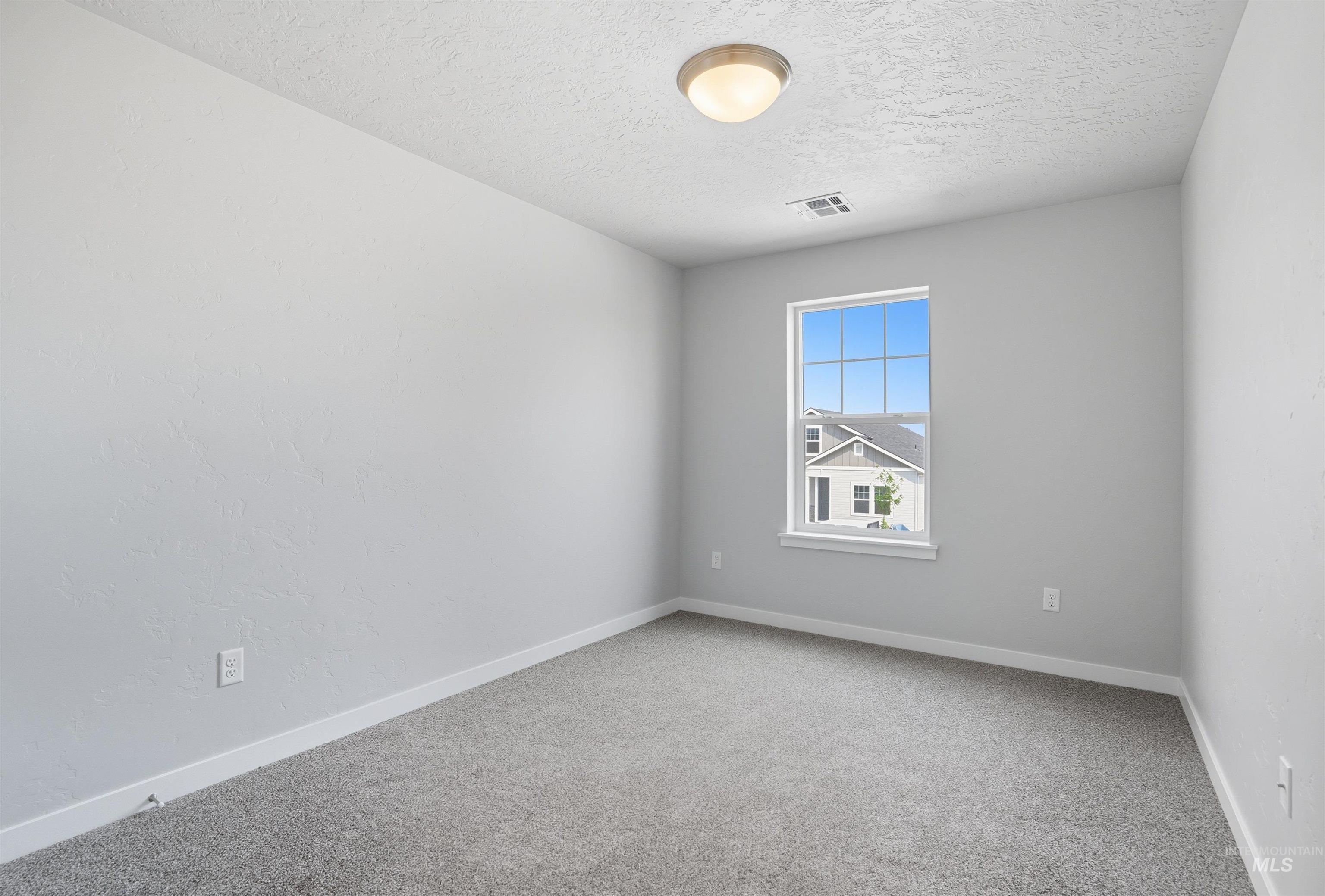 Room featuring light gray textured walls, gray carpet flooring, white baseboards, and a window with white trim