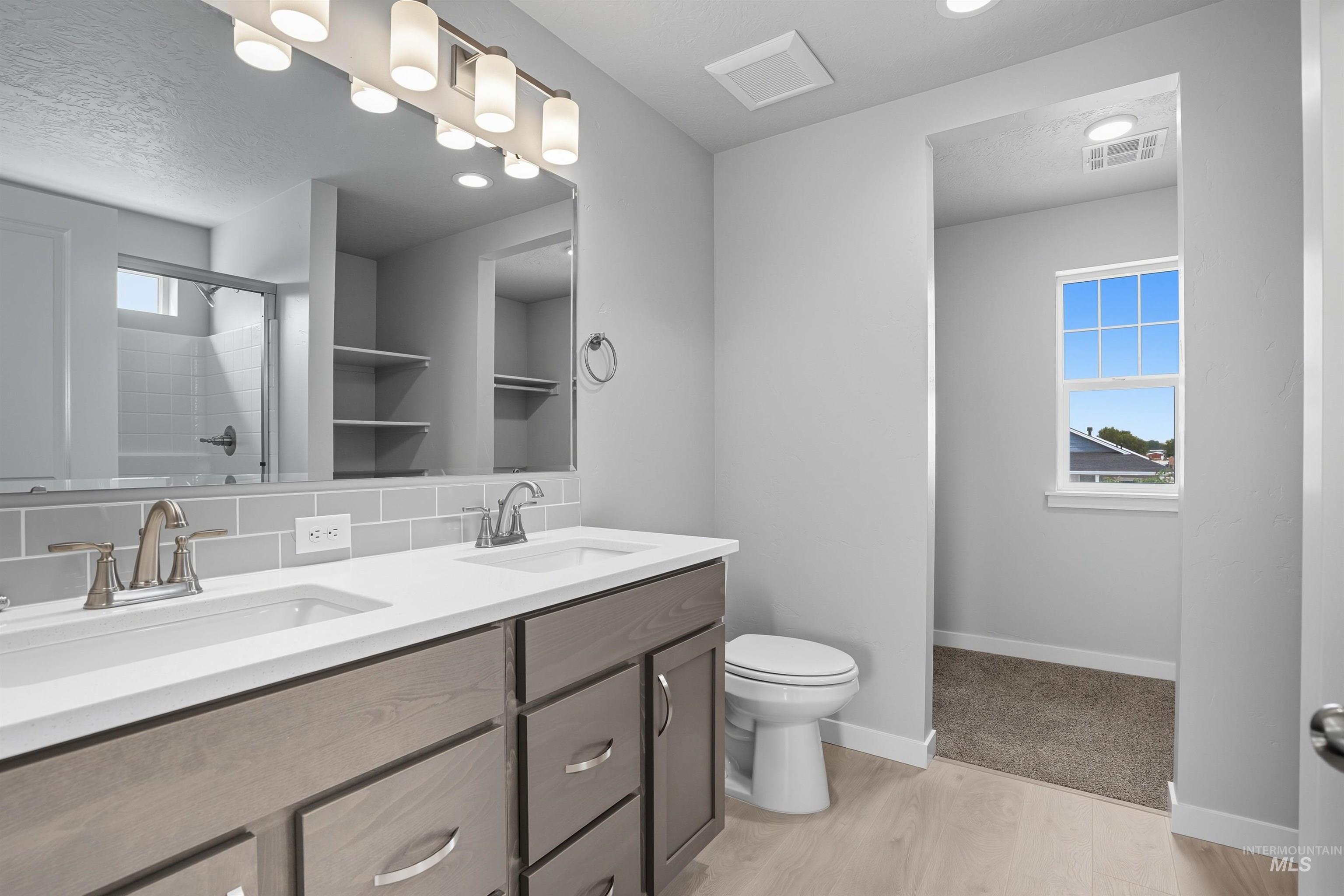 Double vanity with undermount sinks, white countertops, and brushed nickel fixtures