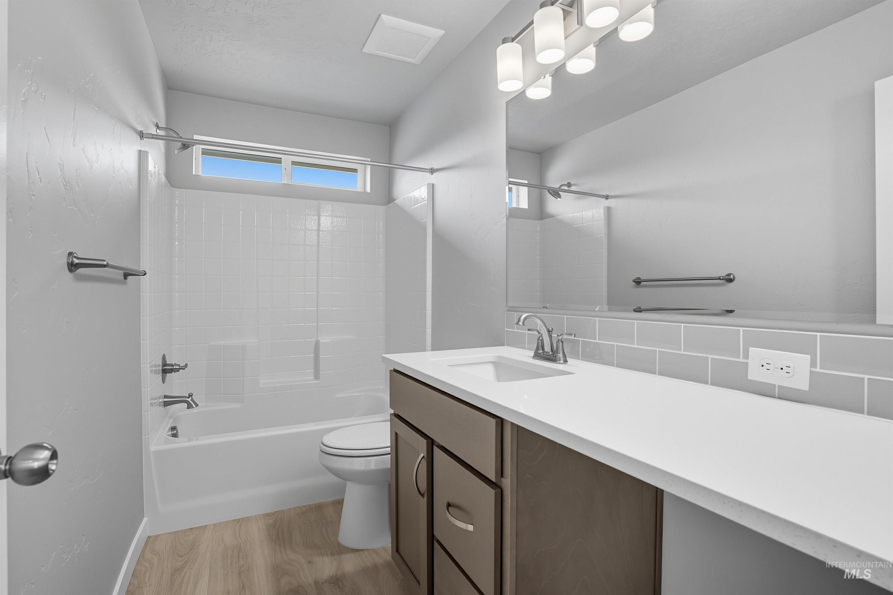 Bathroom featuring a vanity with an integrated sink, a white countertop, and a gray subway tile backsplash