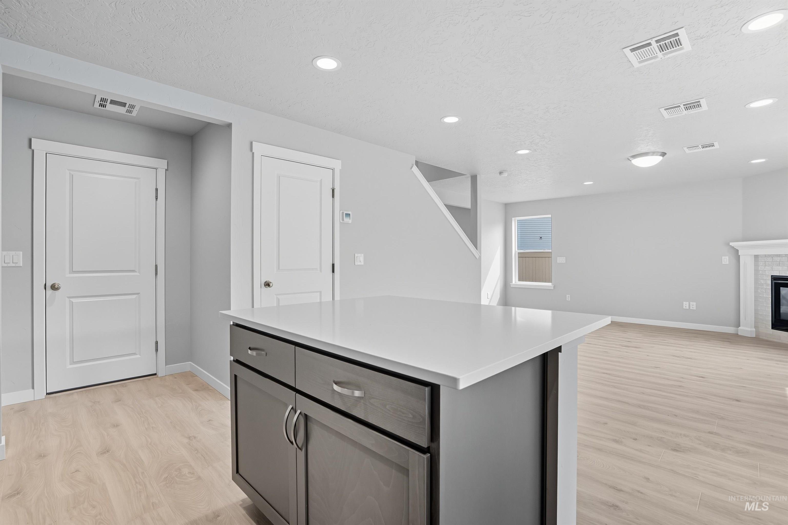 Kitchen island featuring a white countertop and gray cabinetry with silver hardware