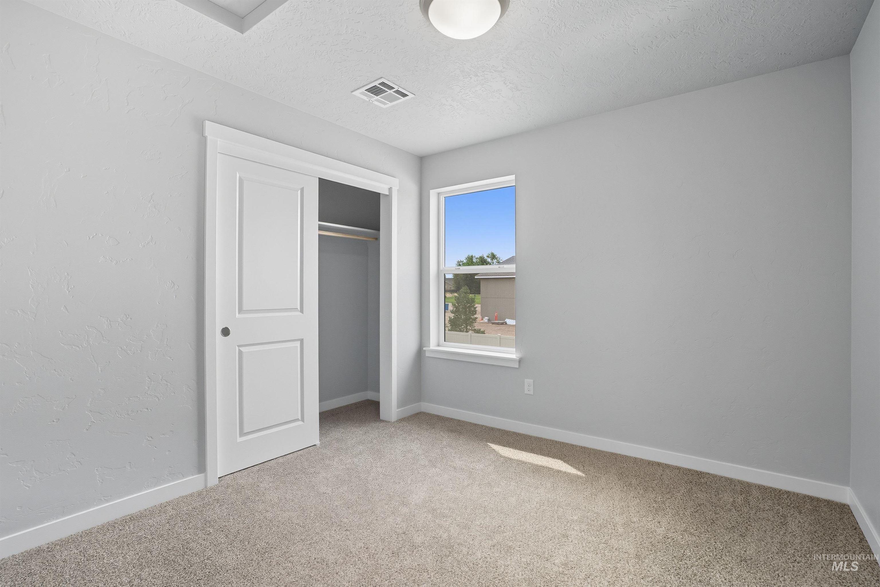 Neutral-toned carpeting, white baseboards, and a single window offering natural illumination