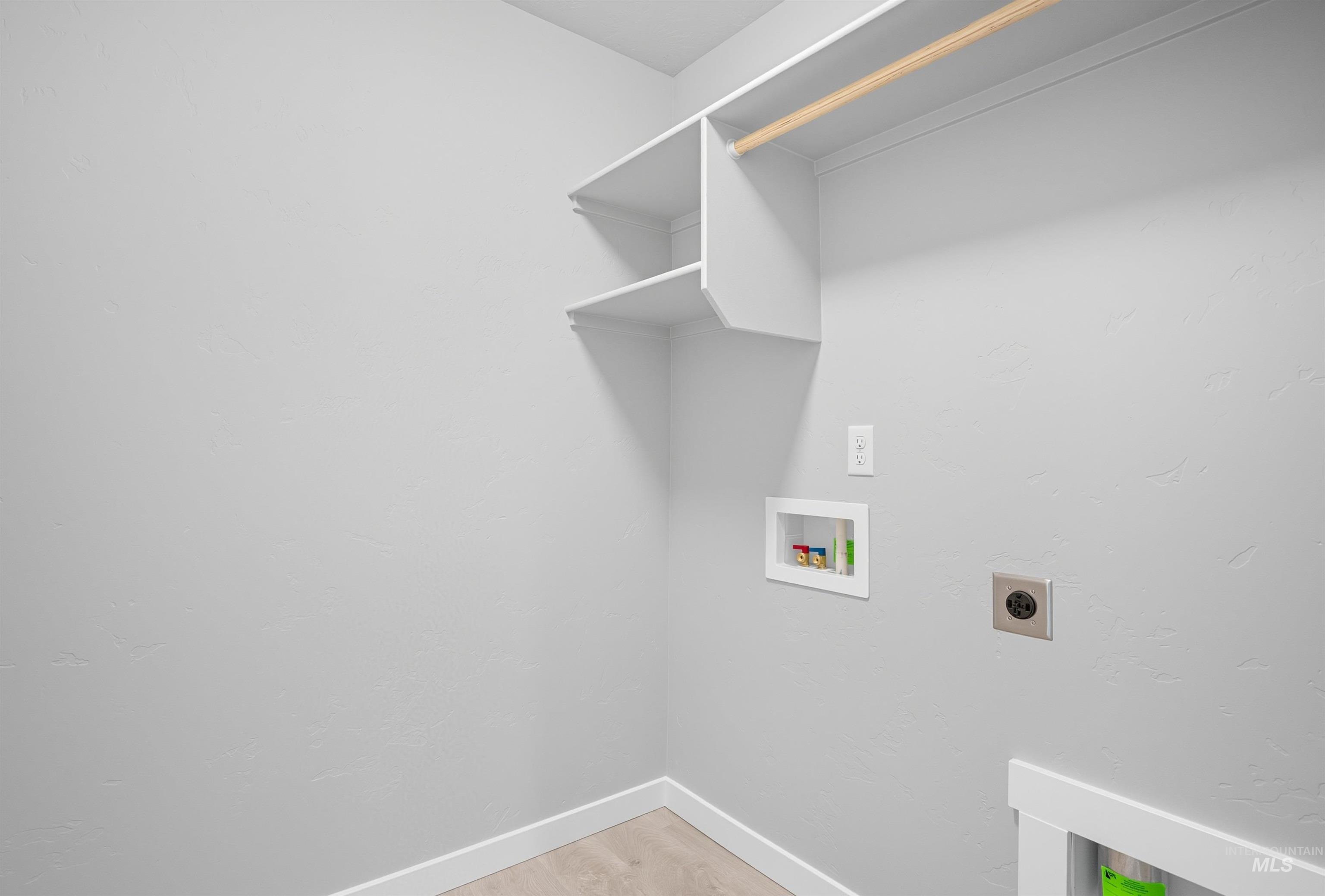Laundry area featuring light wood-finish flooring, white baseboards, and neutral wall paint
