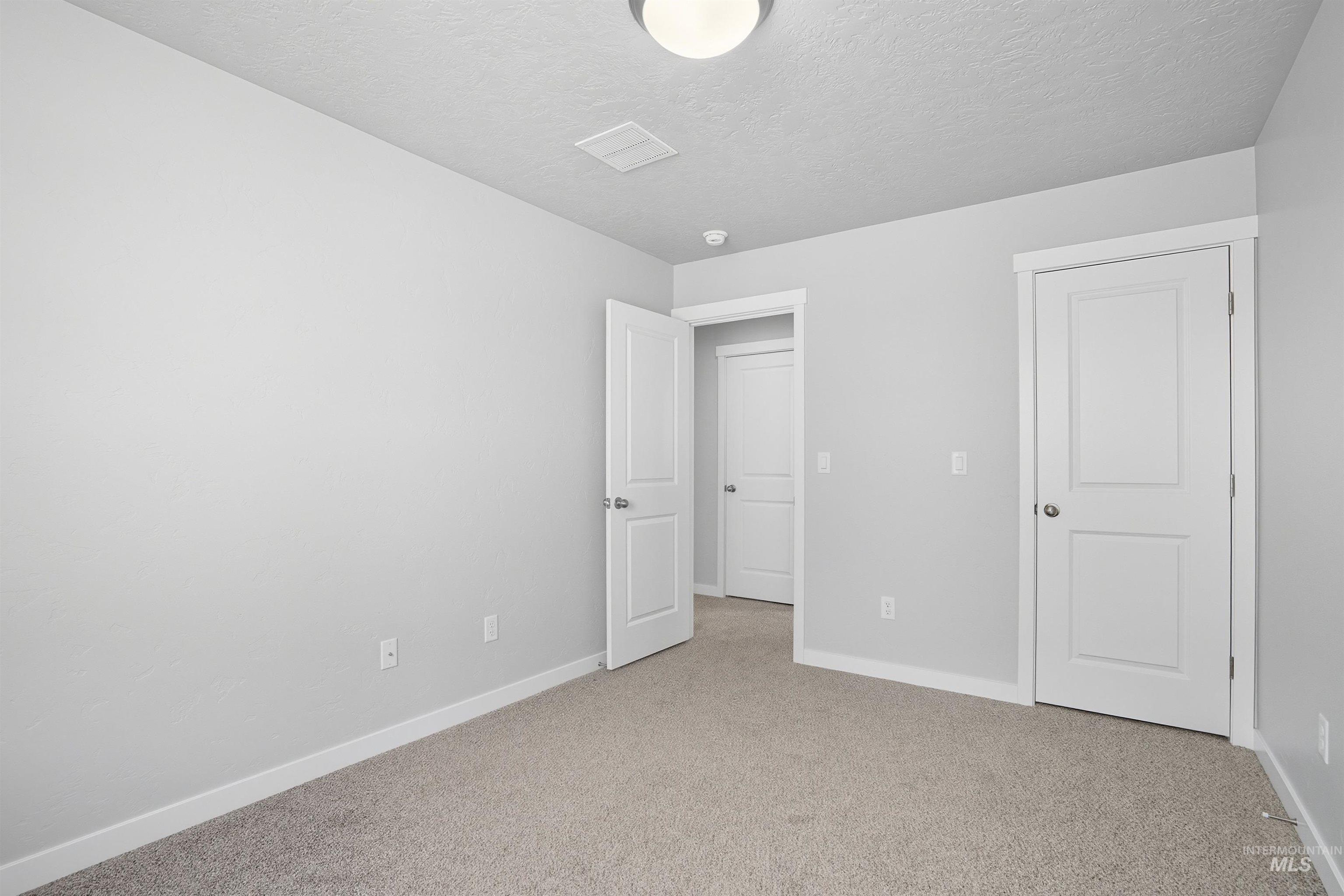 Neutral-toned room featuring light gray walls, white trim, and plush carpet flooring