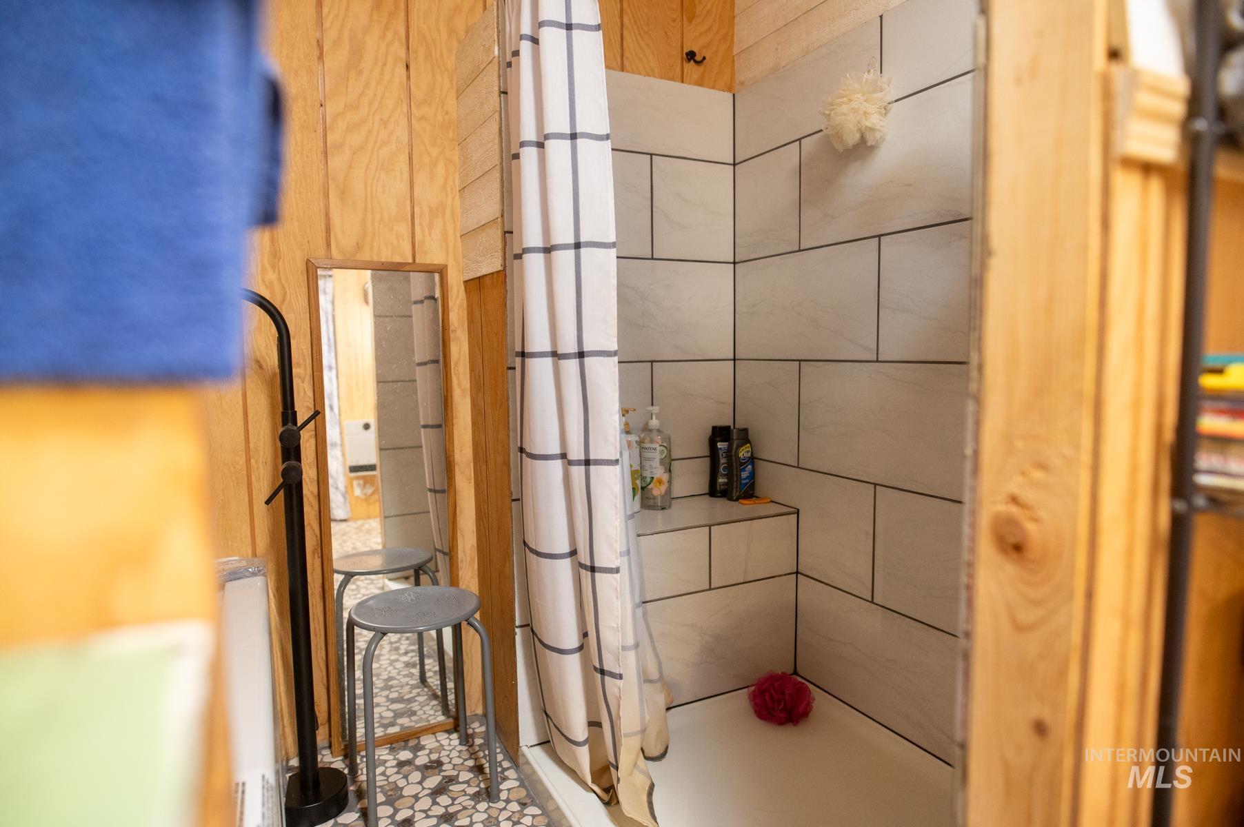 Shower enclosure featuring white subway tile surround, integrated shower bench, and a white shower pan