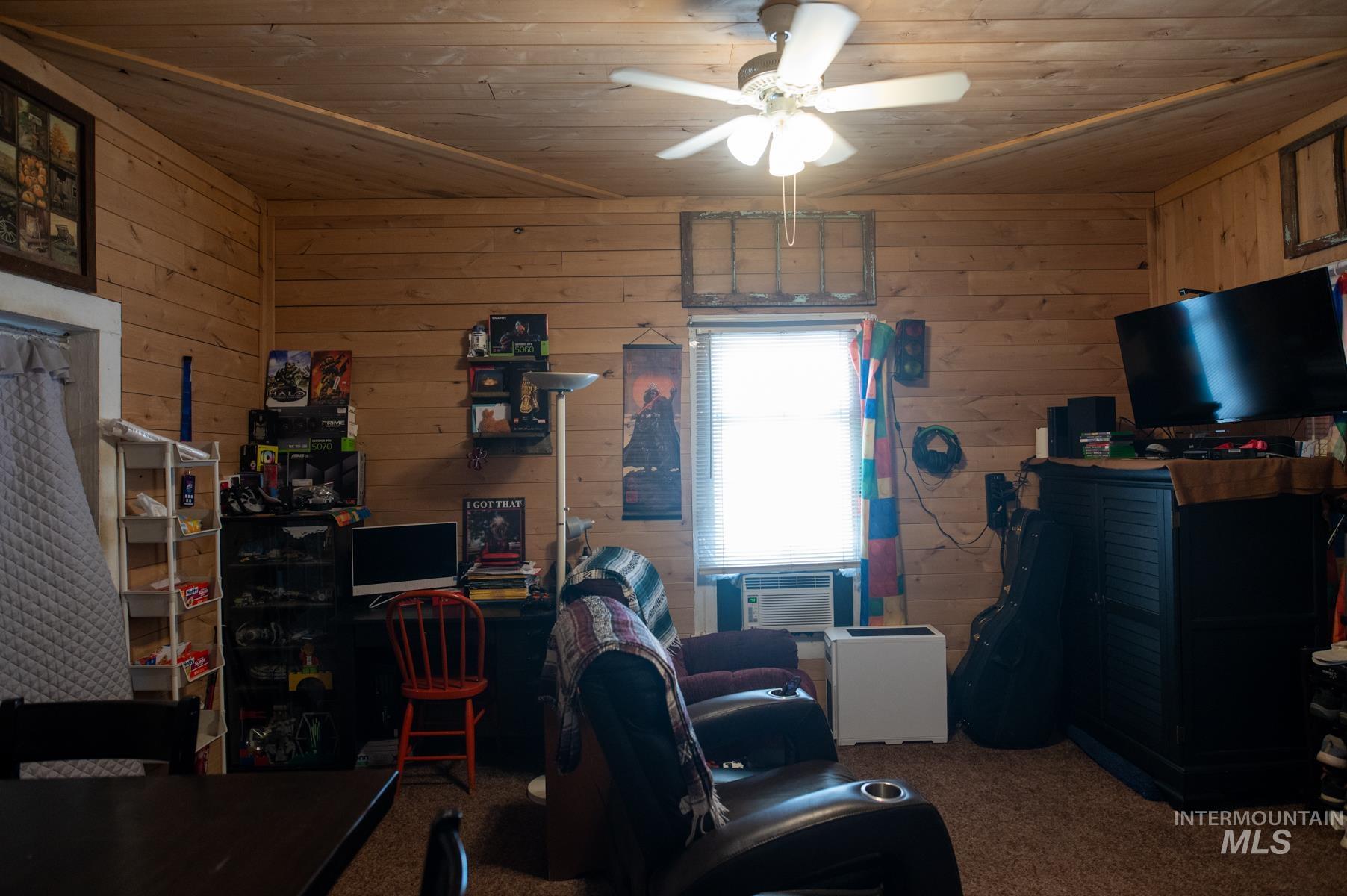 Wood-paneled room featuring a ceiling fan with light, single window, and textile wall hangings