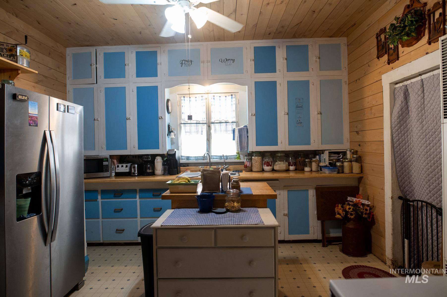 Kitchen featuring light blue and white cabinetry, wood-finish countertops, and wood-paneled walls
