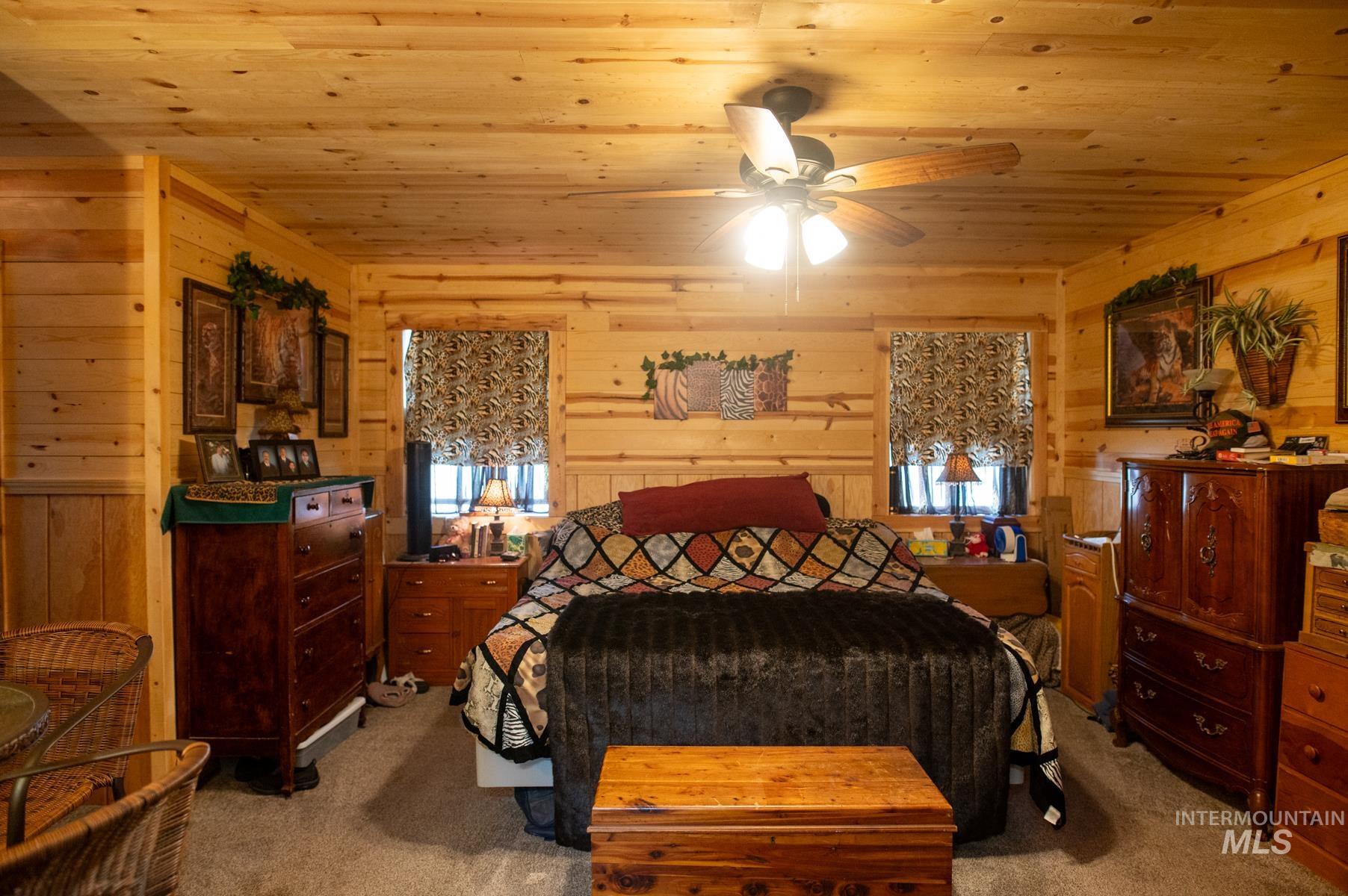 Wood-paneled room featuring a ceiling fan with integrated lighting, wood-finish walls, and plush carpeting