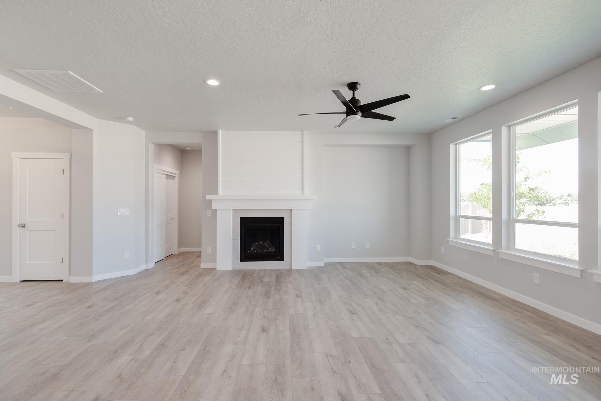 Unfurnished living room featuring a fireplace, recessed lighting, a ceiling fan, light wood-style flooring, and a textured ceiling
