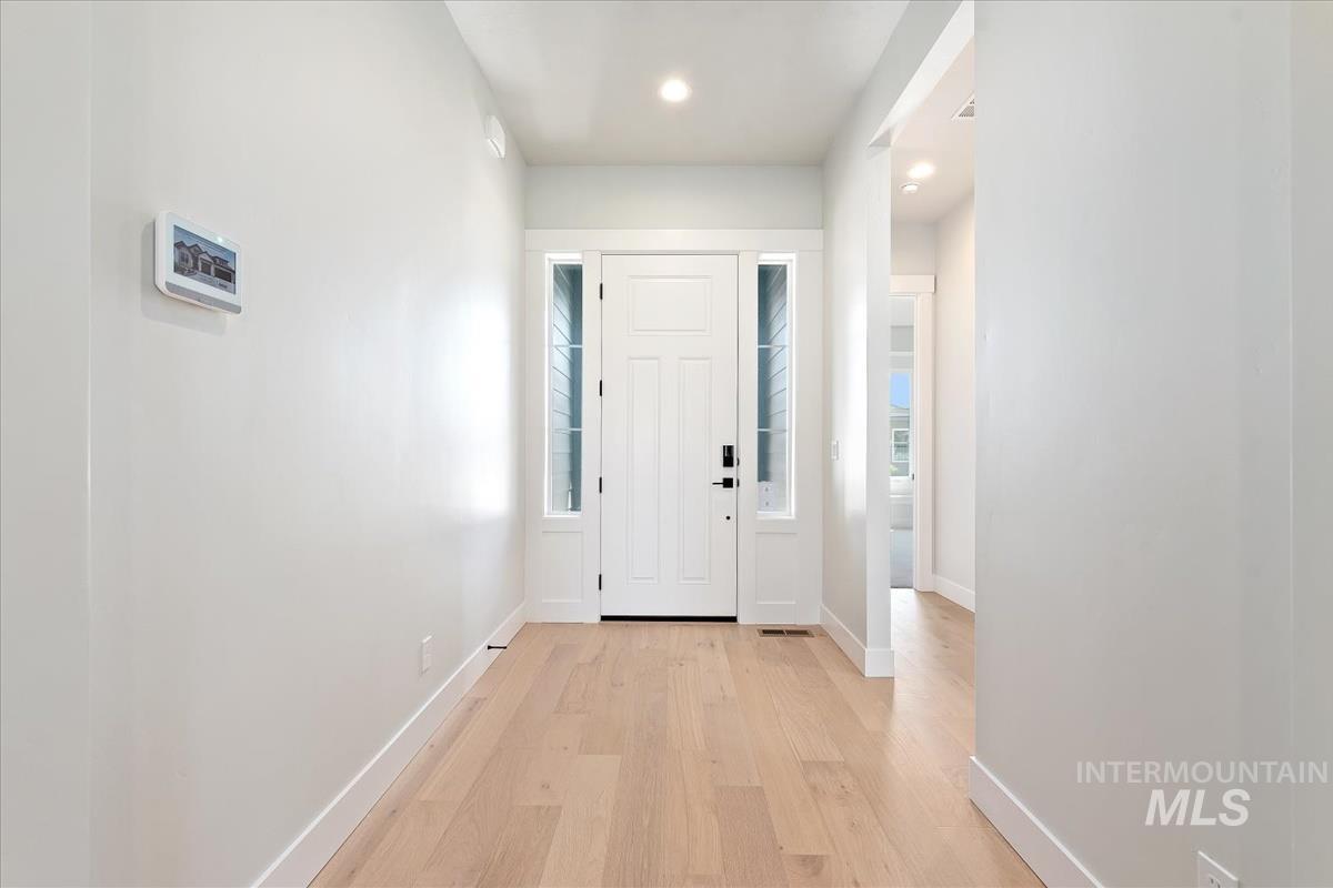 Foyer entrance with light wood finished floors and recessed lighting