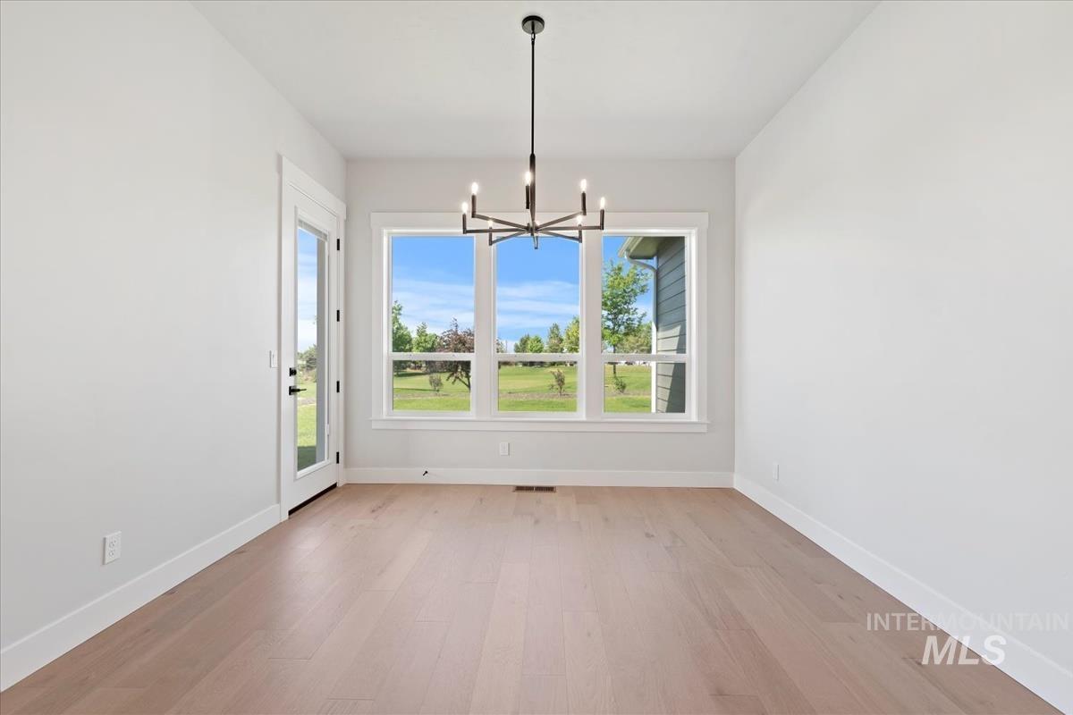 Unfurnished dining area with light wood finished floors and a chandelier