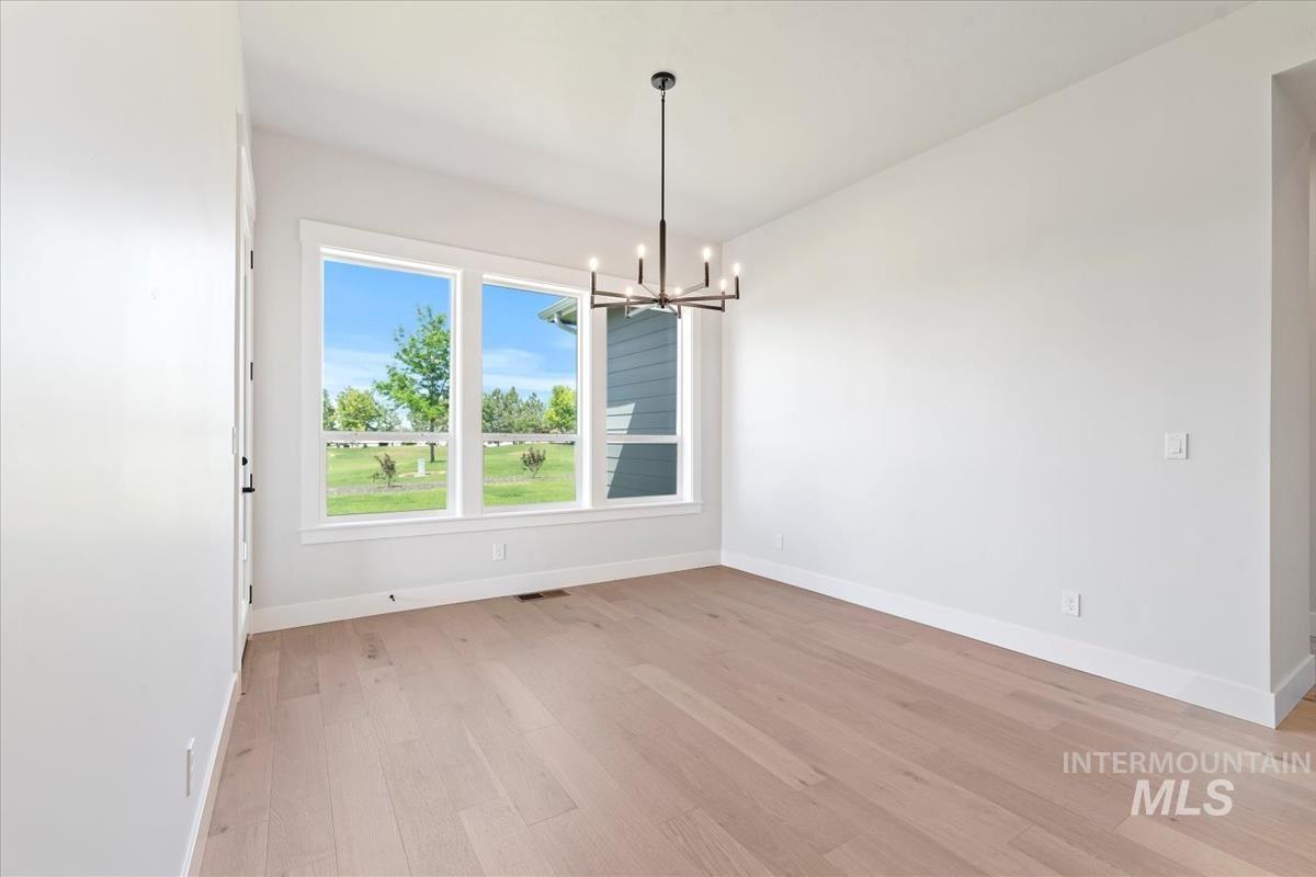 Unfurnished dining area with a chandelier and light wood-style floors