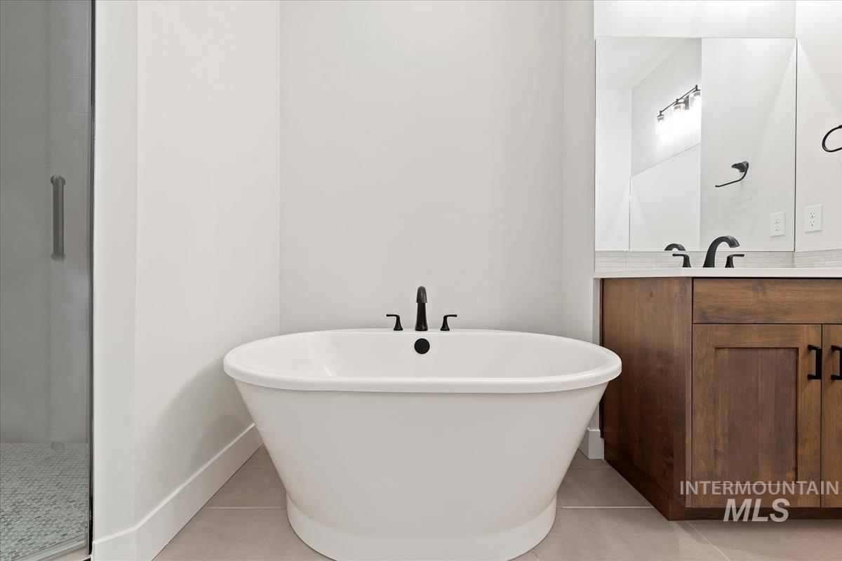 Full bathroom with vanity, light tile patterned floors, a freestanding bath, and a stall shower