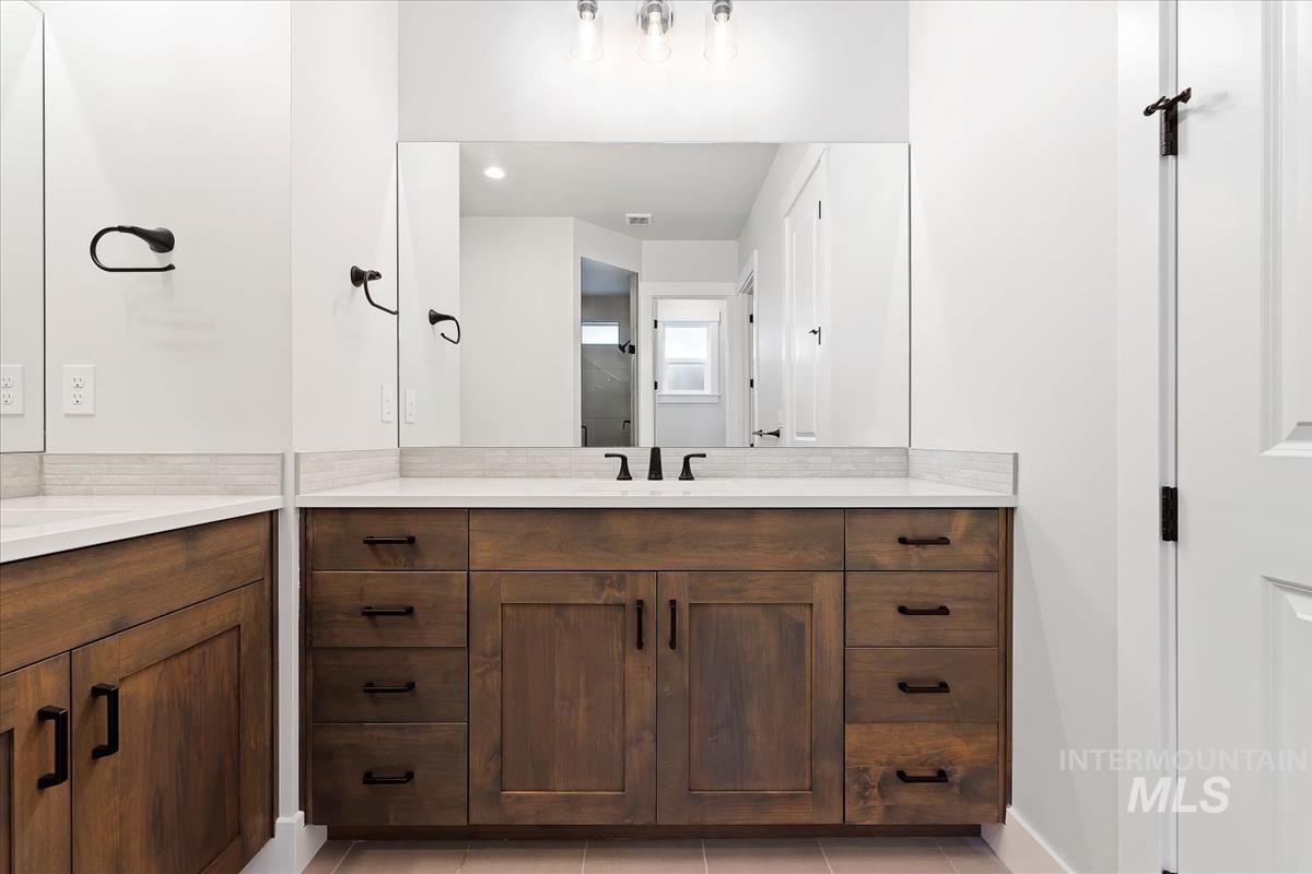 Full bath with two vanities and light tile patterned floors