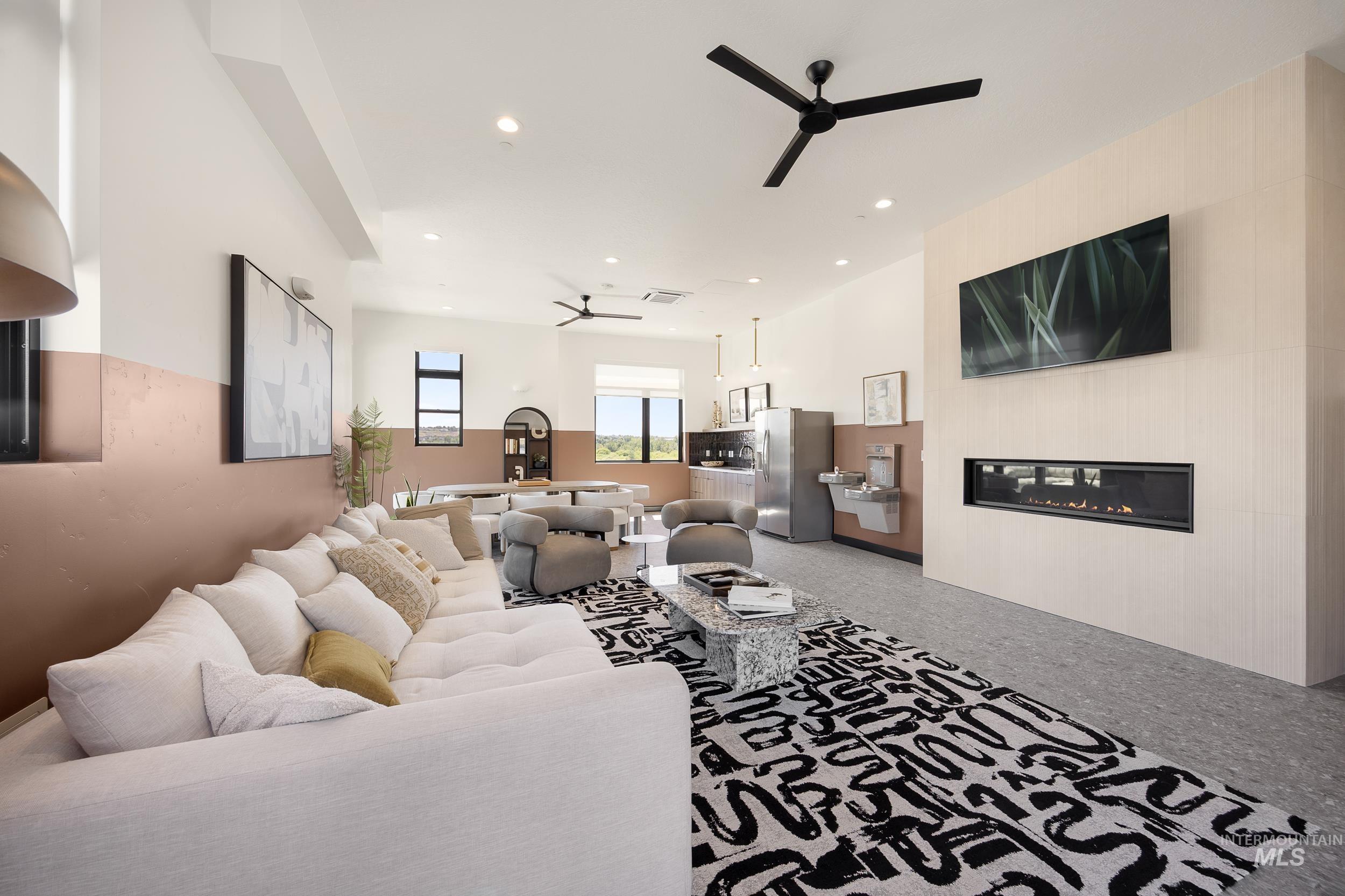 Living room with ceiling fan, a glass covered fireplace, and recessed lighting