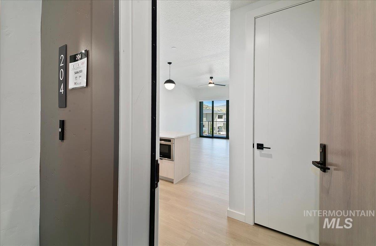 Corridor featuring a textured ceiling and light wood-style floors