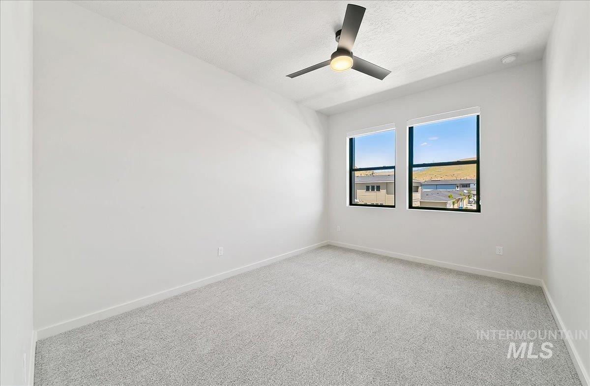 Unfurnished room featuring carpet floors, a textured ceiling, and ceiling fan