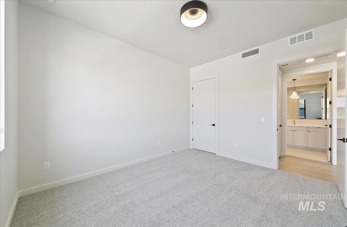 Unfurnished bedroom featuring light colored carpet and ensuite bath