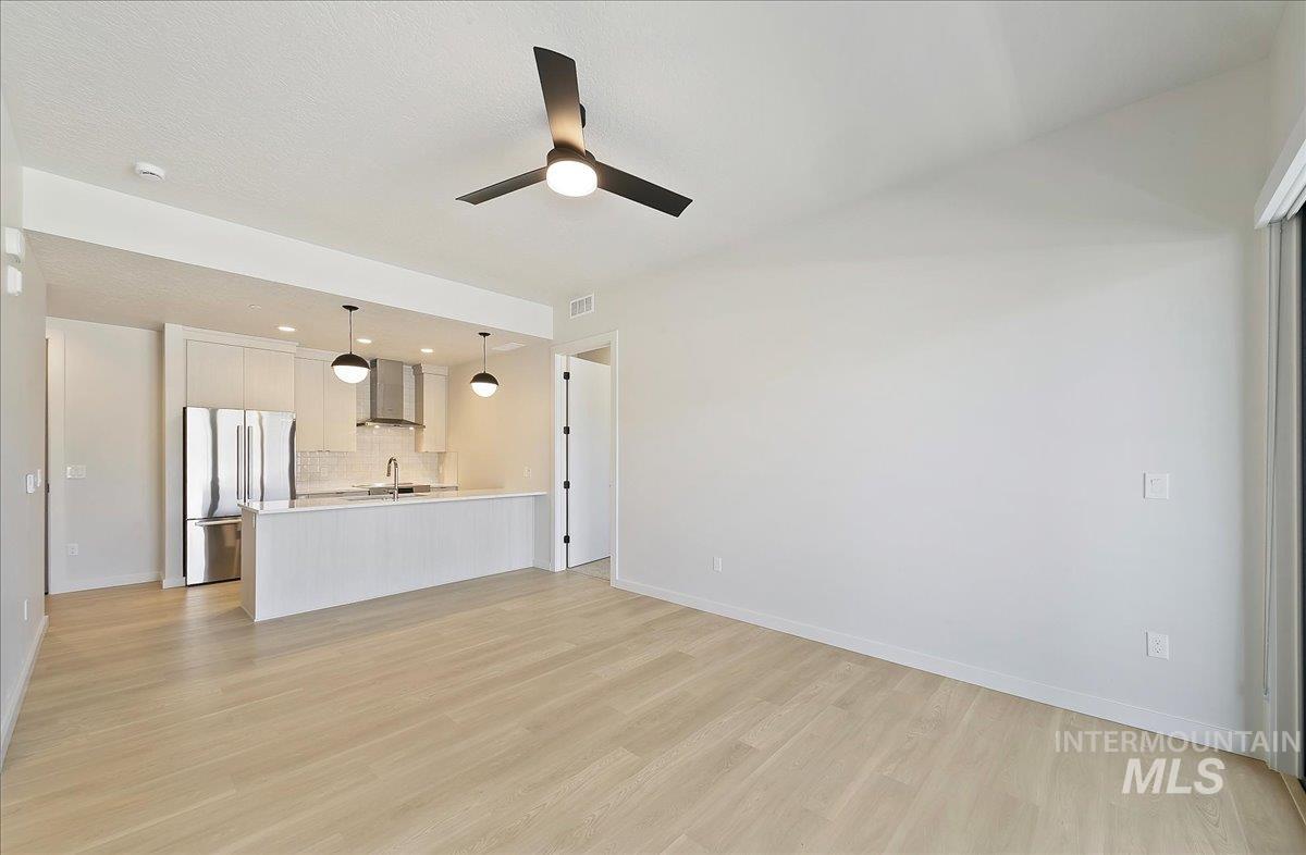 Unfurnished living room with light wood-type flooring, a ceiling fan, and recessed lighting