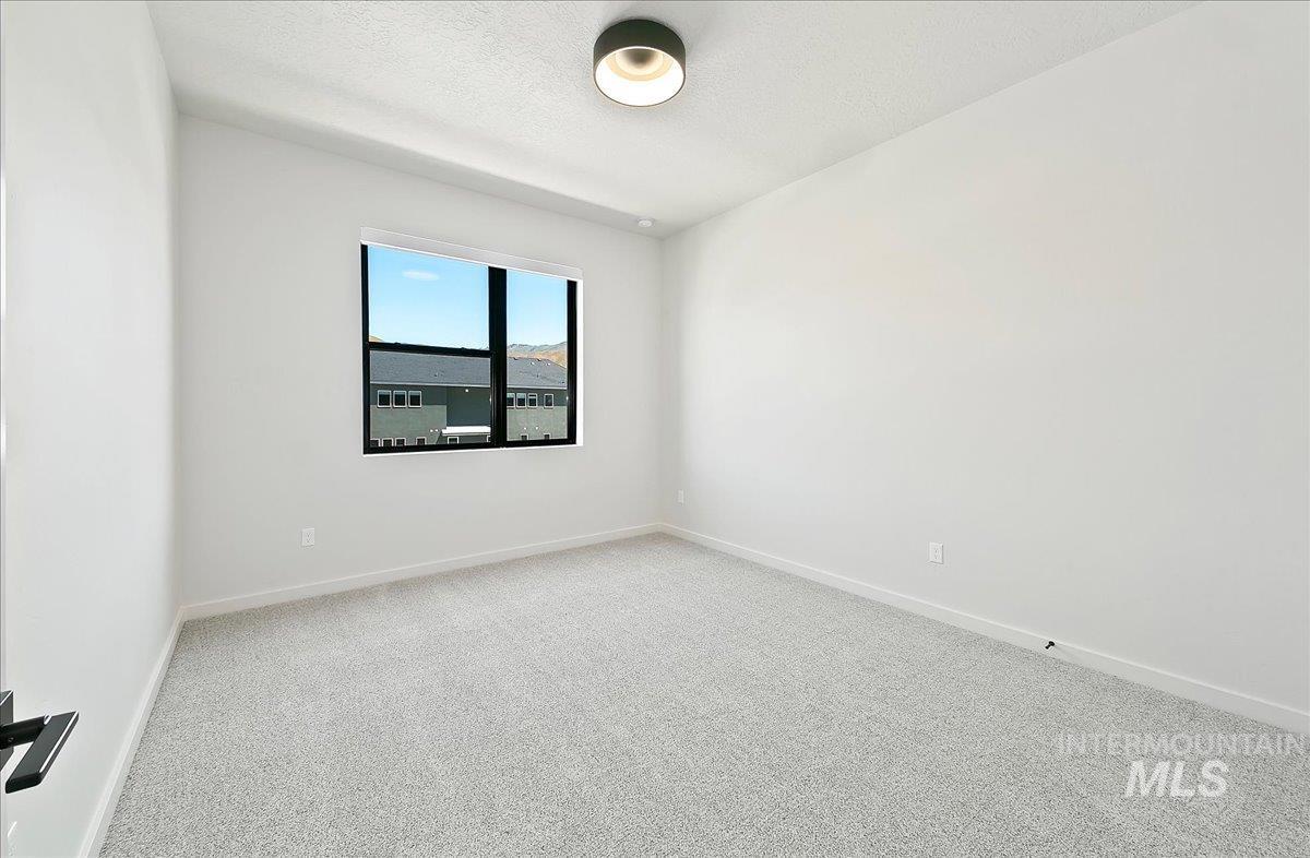 Carpeted empty room featuring baseboards and a textured ceiling