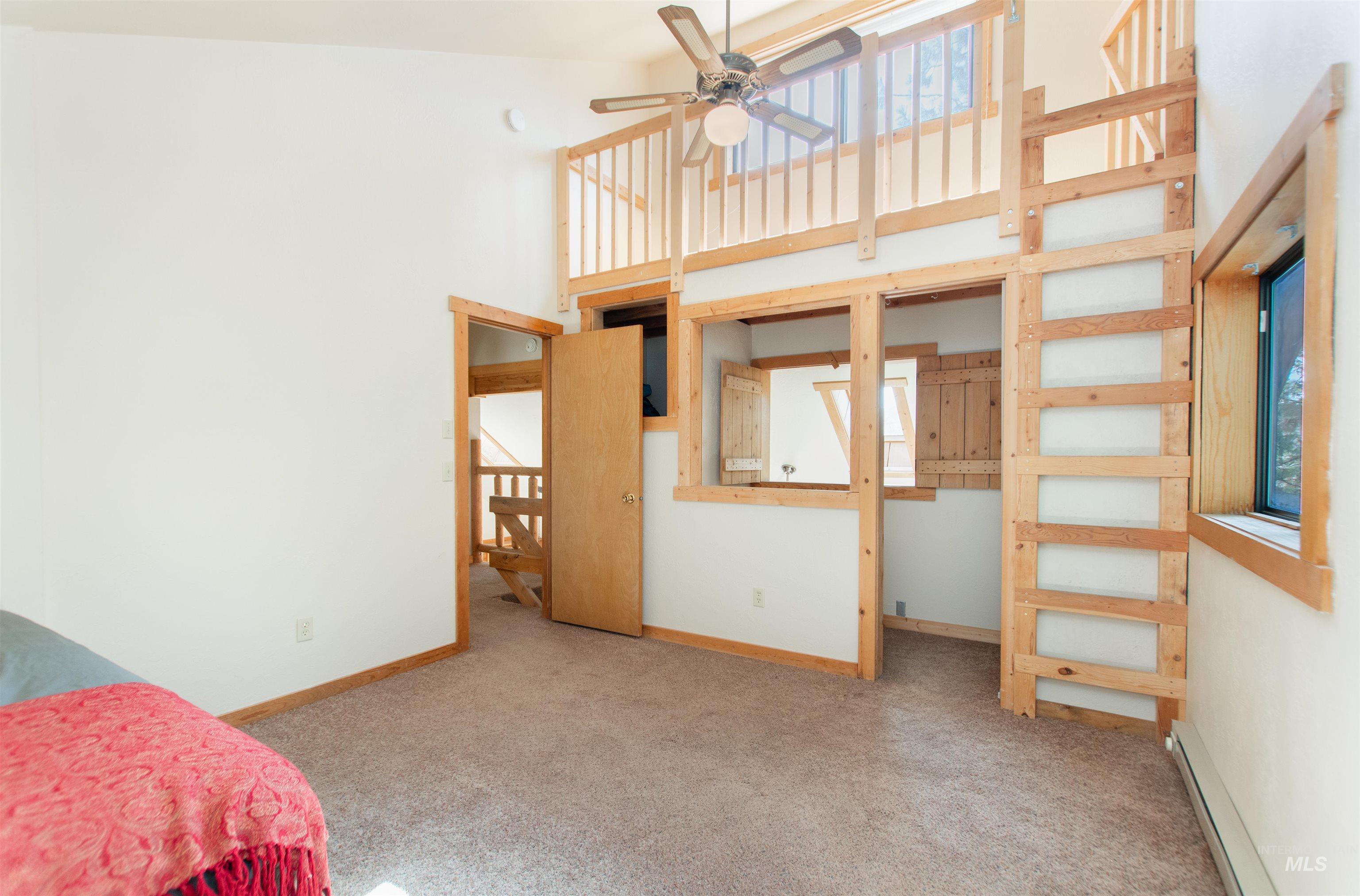 Unfurnished bedroom featuring a high ceiling, a baseboard heating unit, and carpet floors