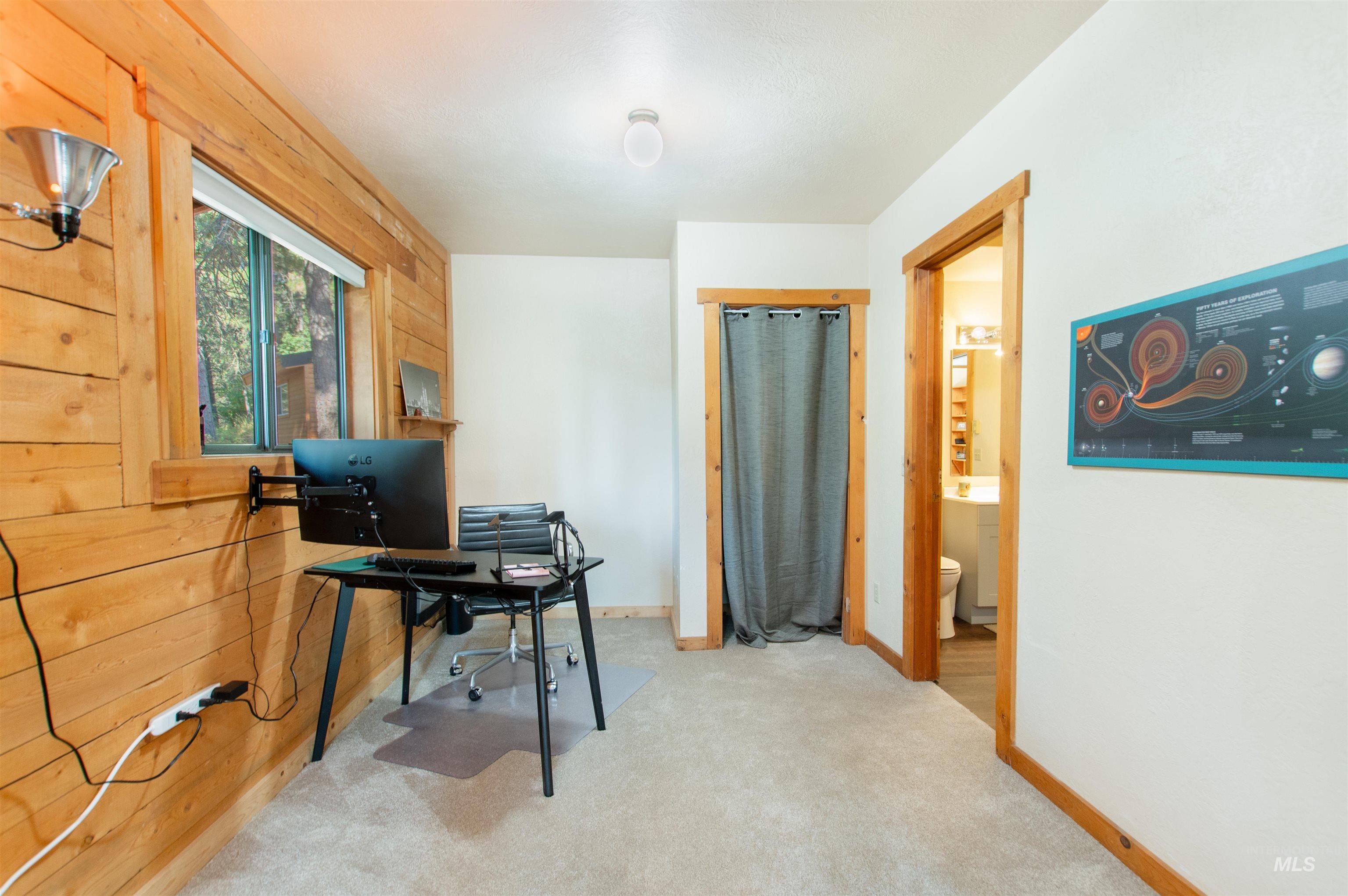 Carpeted office space with baseboards and wooden walls