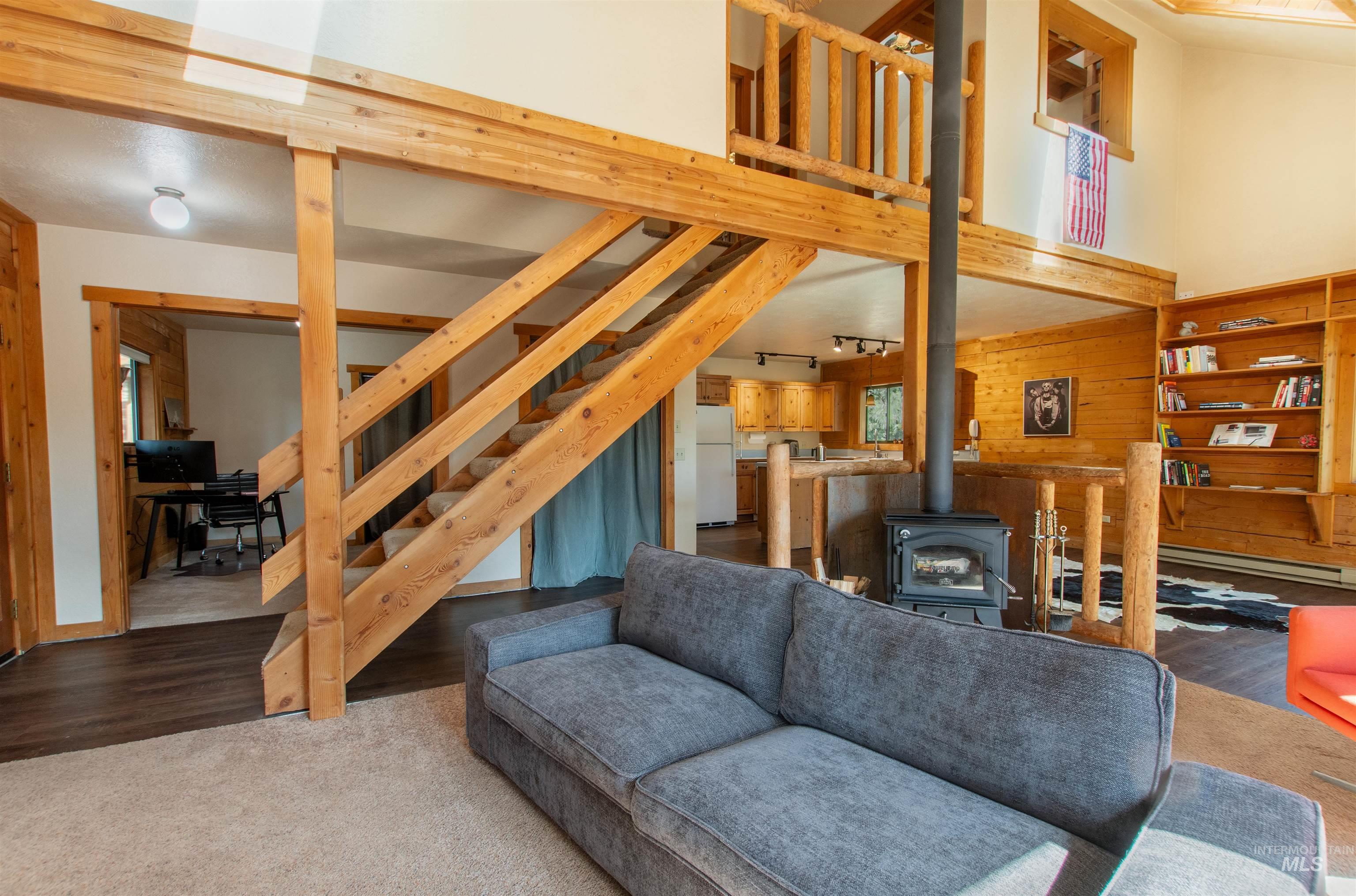 Living area with a wood stove, a high ceiling, stairway, carpet flooring, and wood finished floors