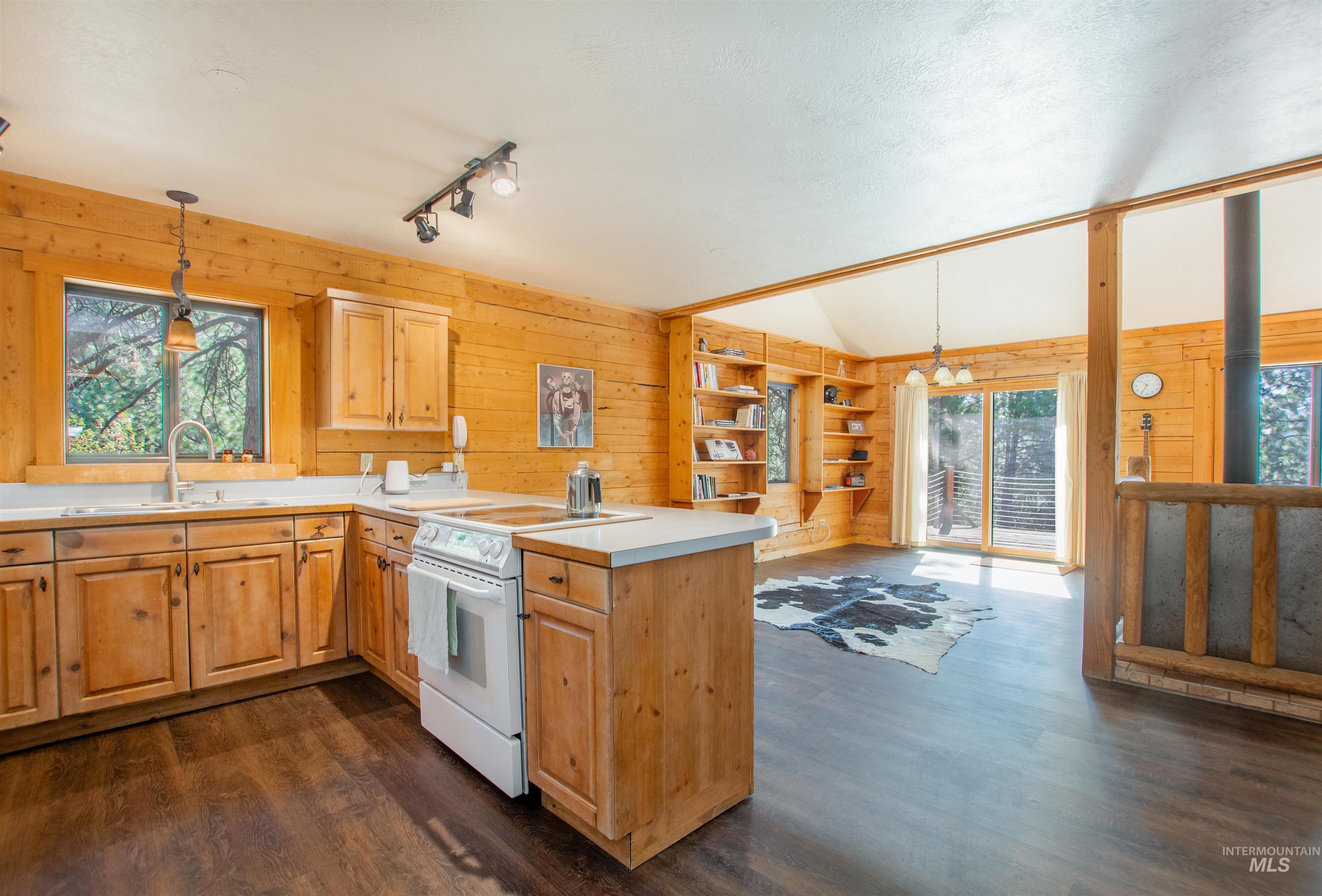 Kitchen featuring wooden walls, white electric stove, a peninsula, dark wood-style flooring, and lofted ceiling
