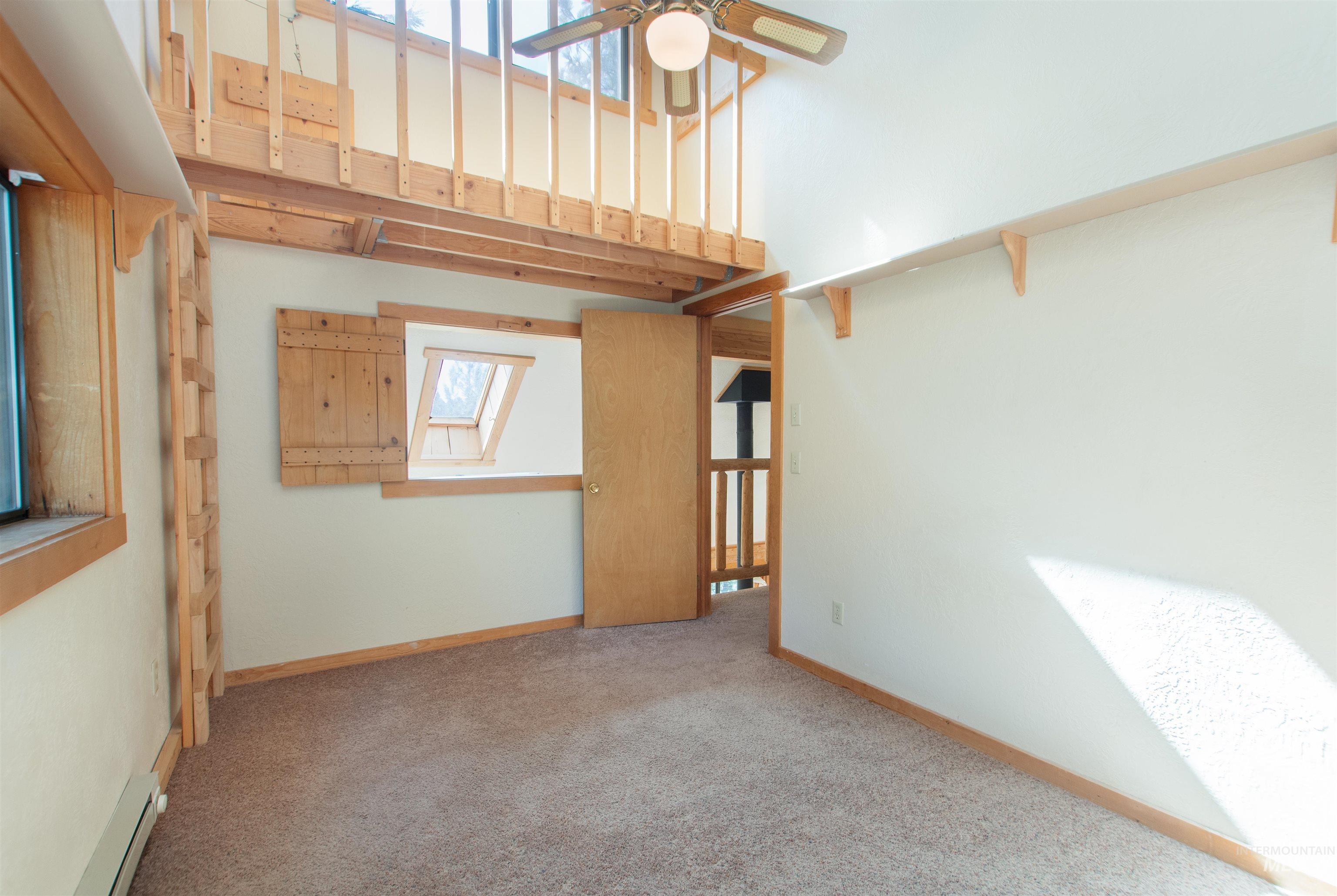 Carpeted empty room featuring a skylight, a high ceiling, a baseboard heating unit, and ceiling fan