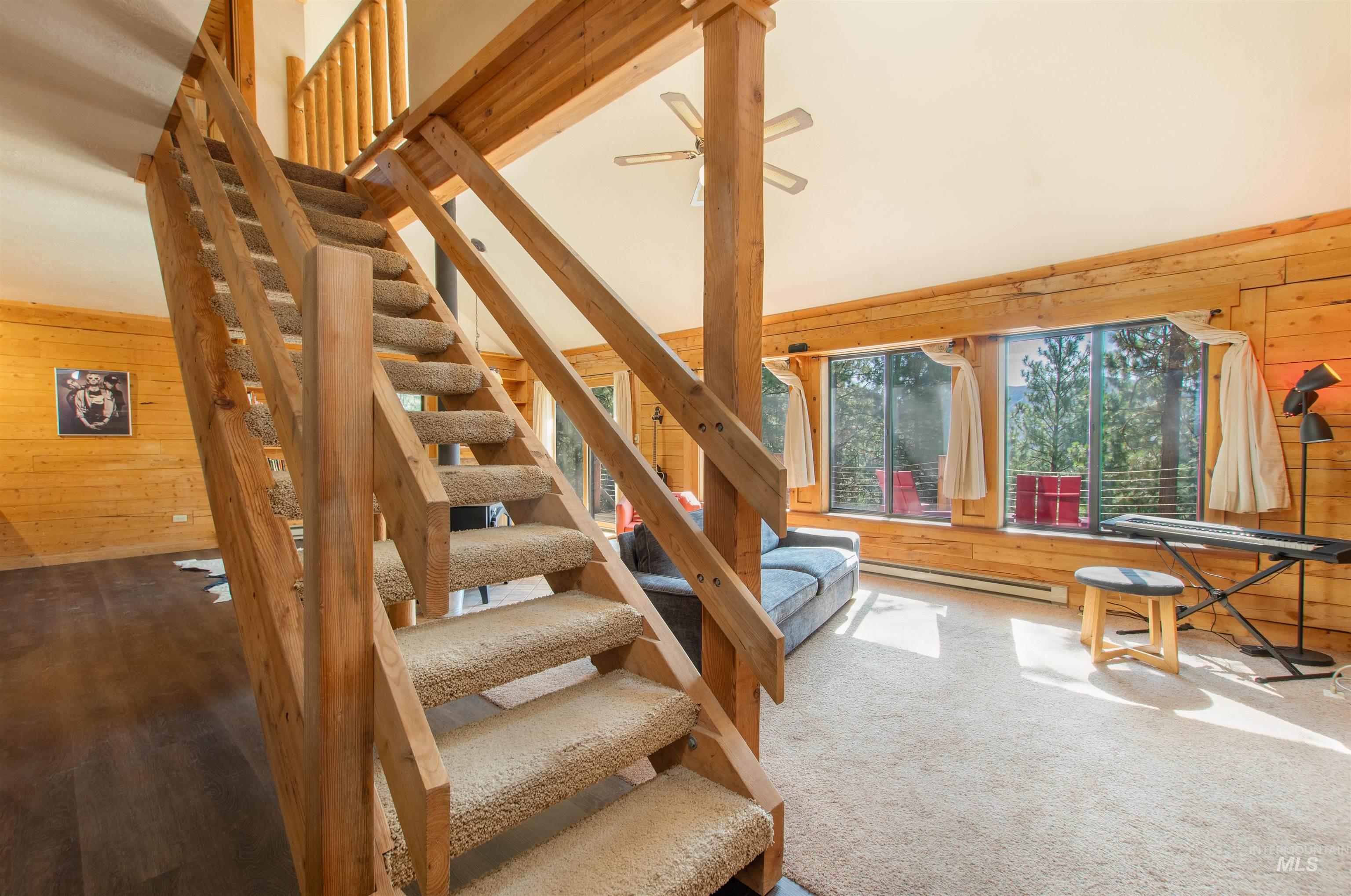 Stairway featuring wooden walls, a baseboard radiator, a ceiling fan, and a towering ceiling