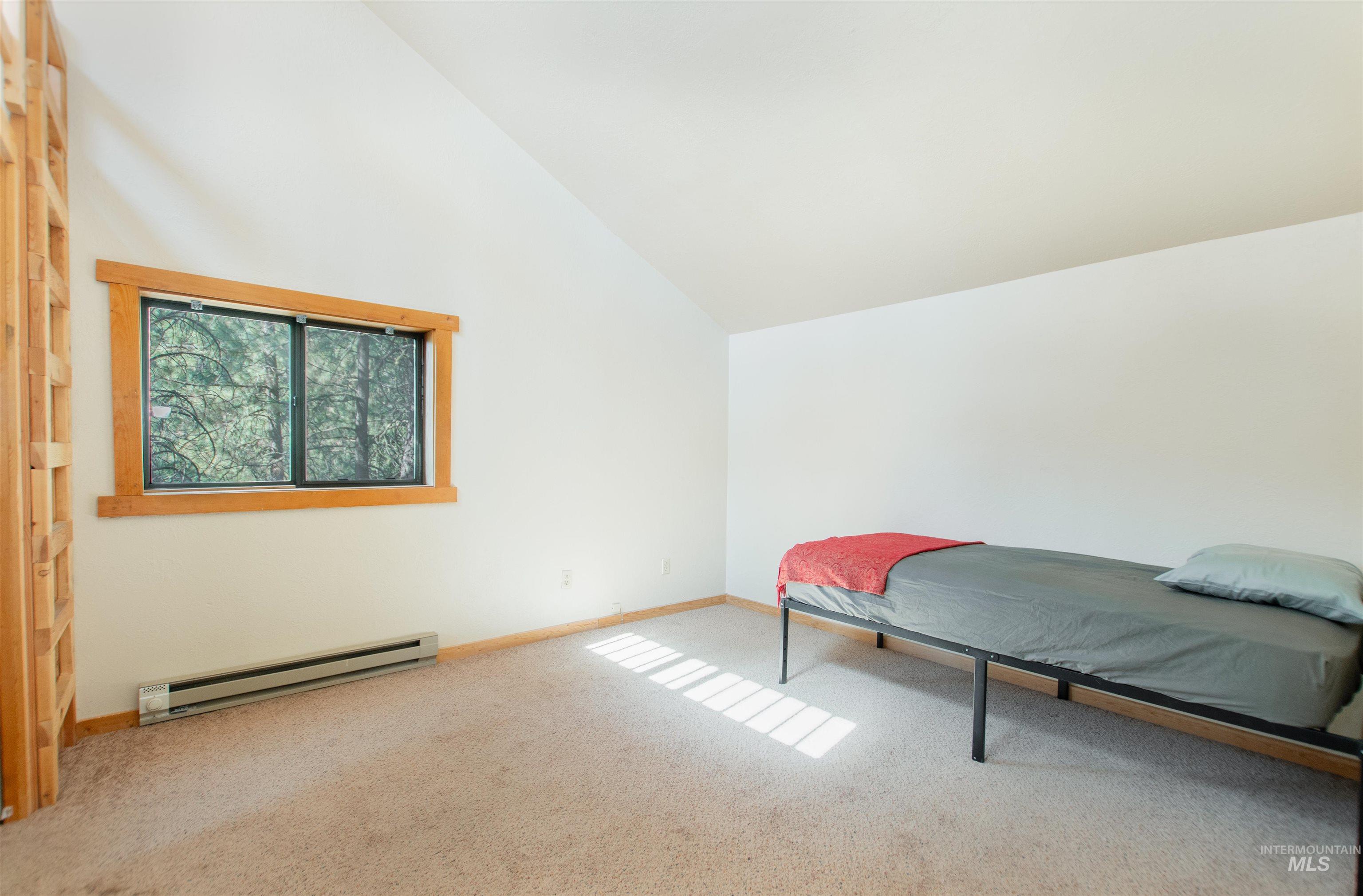 Bedroom featuring baseboard heating, carpet flooring, and high vaulted ceiling