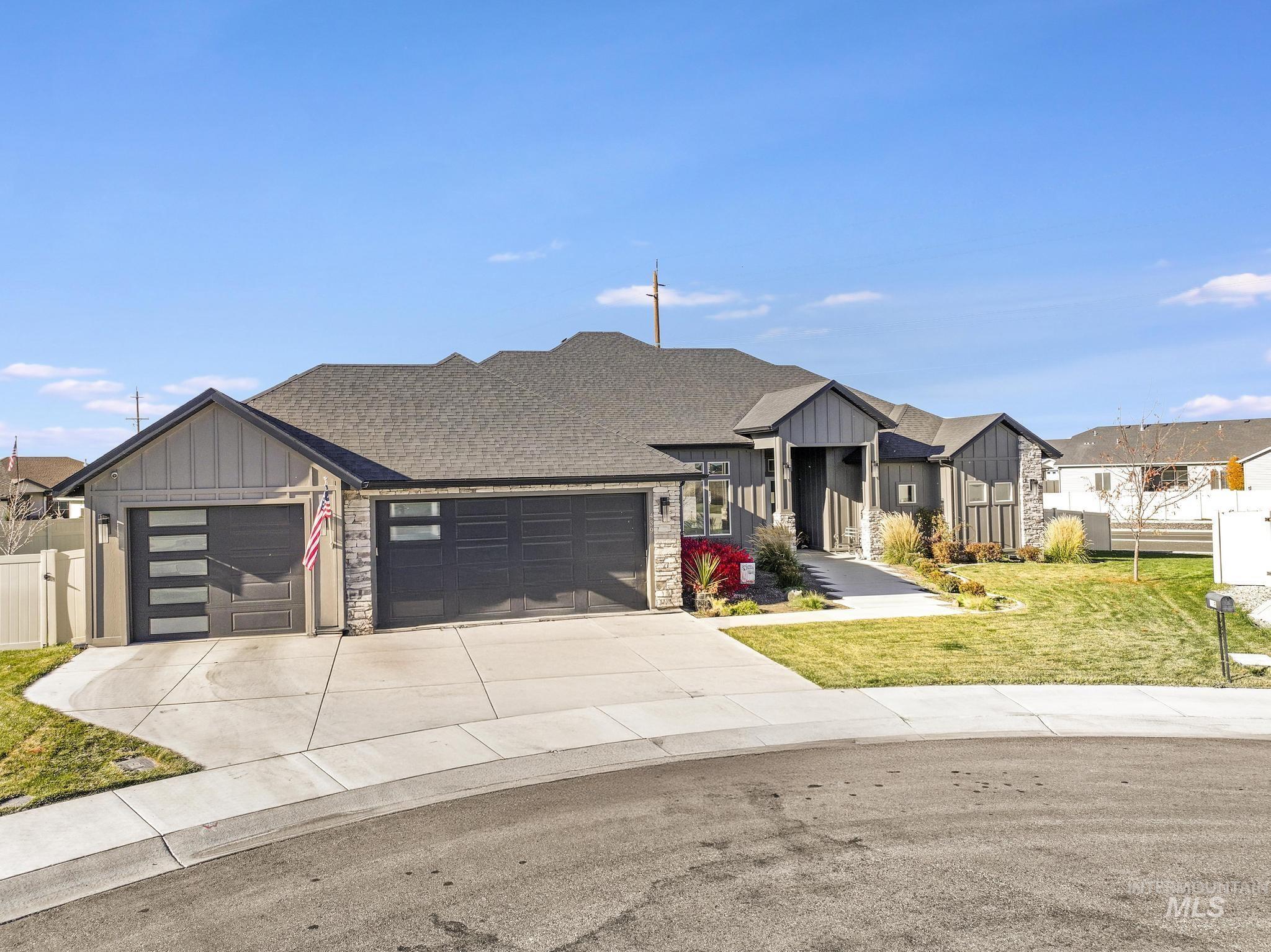 View of front of property featuring board and batten siding, a garage, driveway, and stone siding